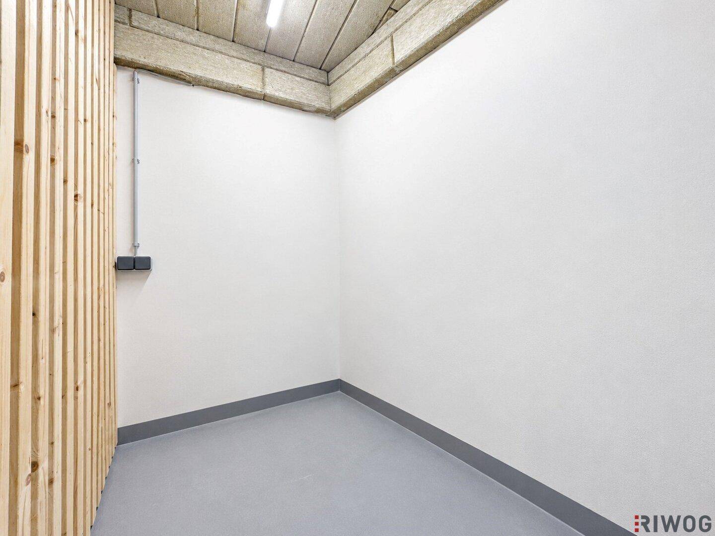 Kellerabteil oder Abstellraum mit grauem Boden und einer Holzwandverkleidung.
