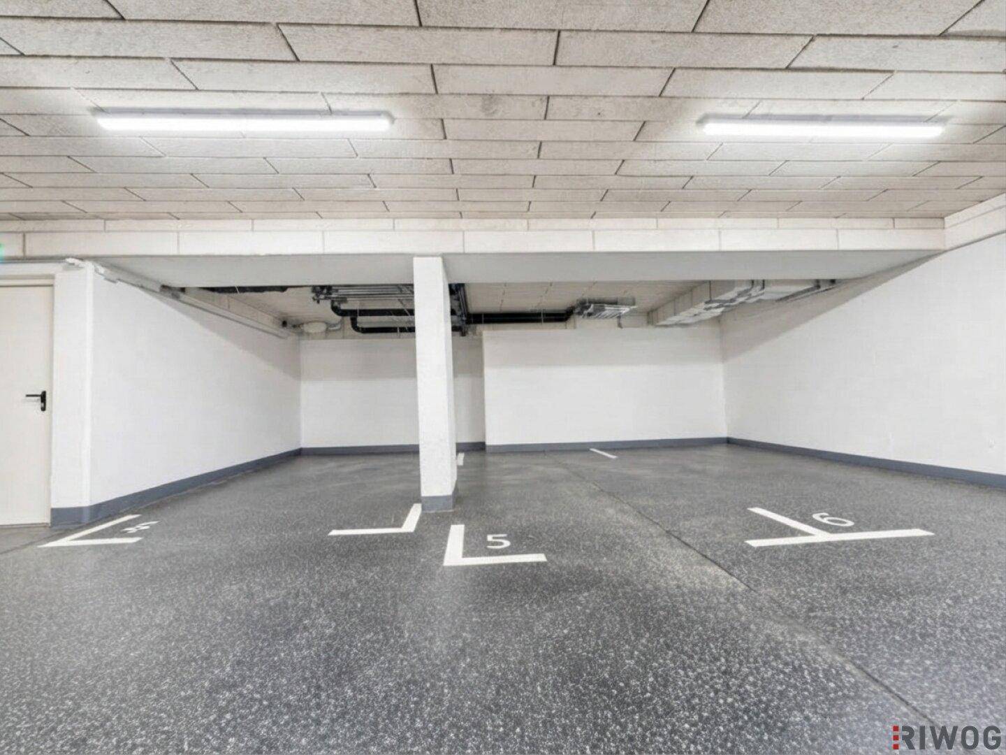 Saubere Tiefgarage mit klar markierten Parkplätzen und effizienter Deckenbeleuchtung.