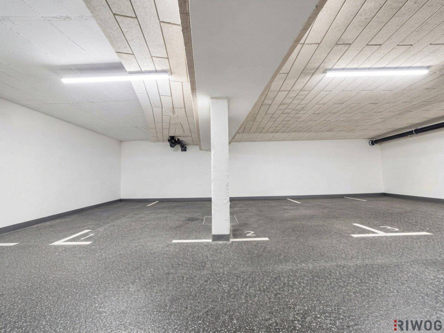 Geräumige Tiefgarage mit markierten Stellplätzen und heller Beleuchtung für mehrere Fahrzeuge.