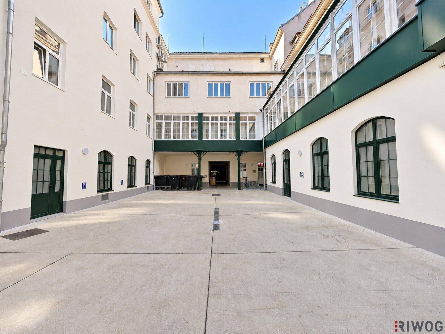 Geräumiger Innenhof mit sauberem Betonboden, umgeben von Gebäuden mit klassischer Architektur.