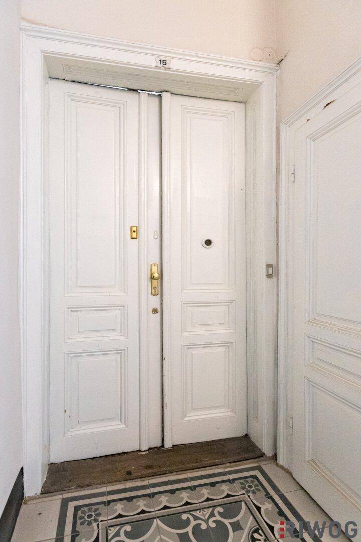 Eingangstür einer Wohnung mit dekorativen Fliesen im Flurbereich, im Altbau-Stil.