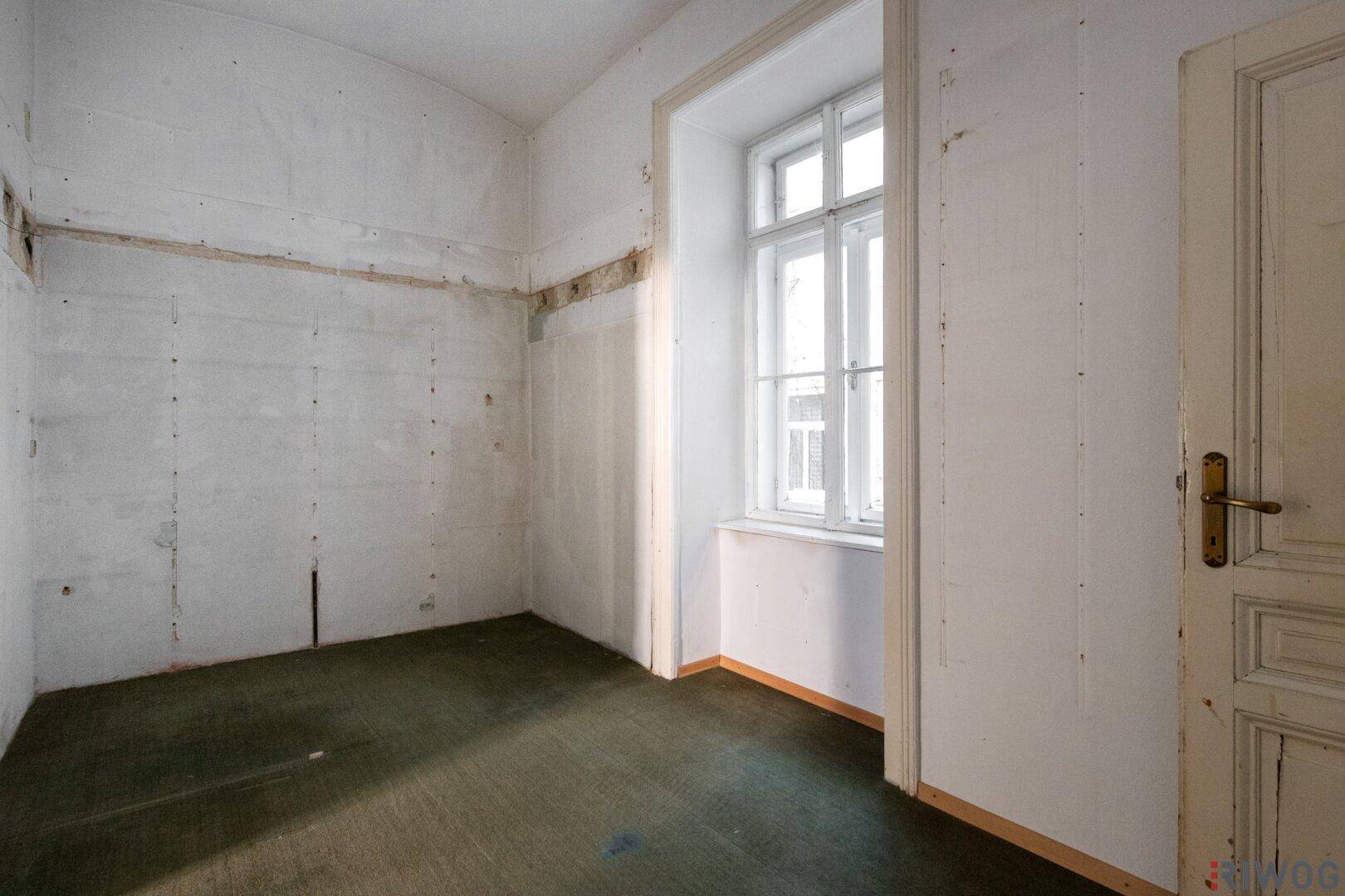 Unmöblierter Raum mit Fenster und grünem Teppichboden, bietet Potenzial für verschiedene Nutzungen.
