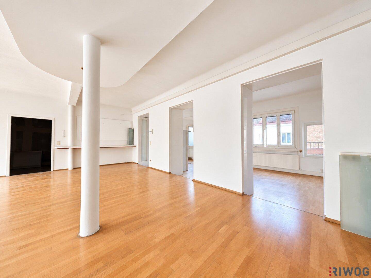 Heller Bürobereich mit Holzboden und offenen Durchgängen zu weiteren Räumen, ideal für flexible Nutzung.