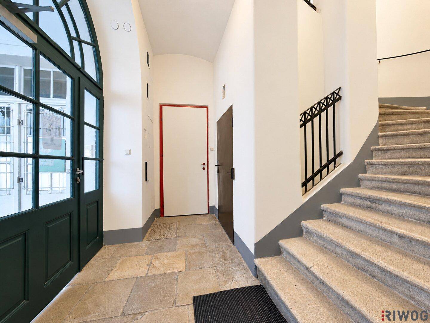 Historischer Eingangsbereich mit Steintreppe und großer grüner Doppeltür, führt ins Gebäude.