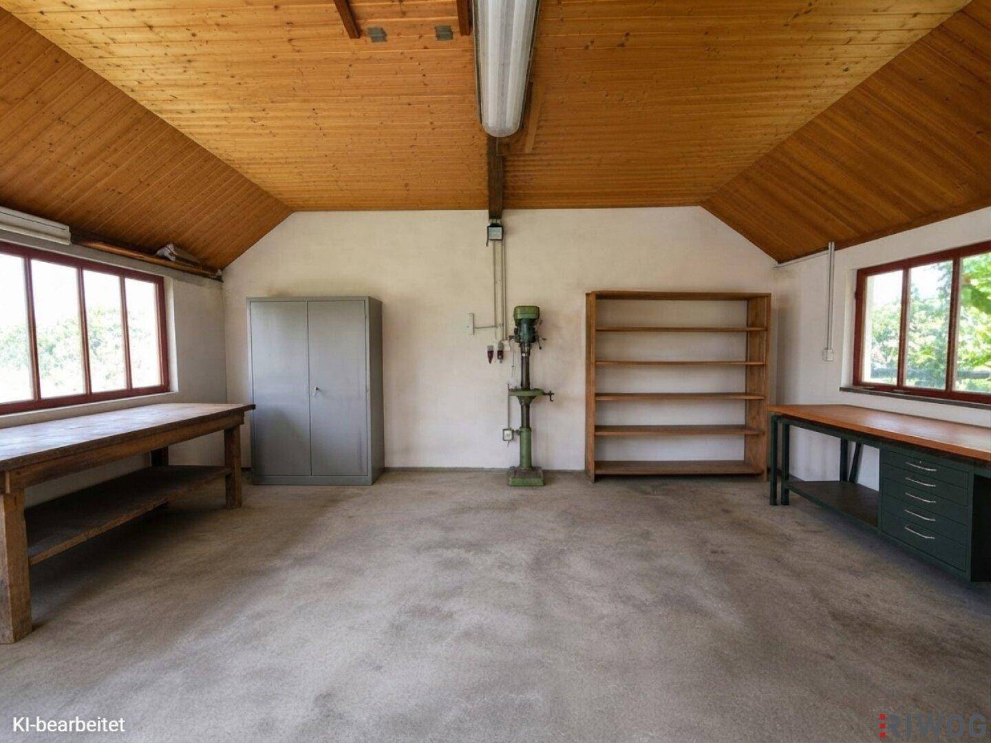 Geräumiger Werkstattraum mit Holzdachschrägen, Werkbänken und großen Fenstern.