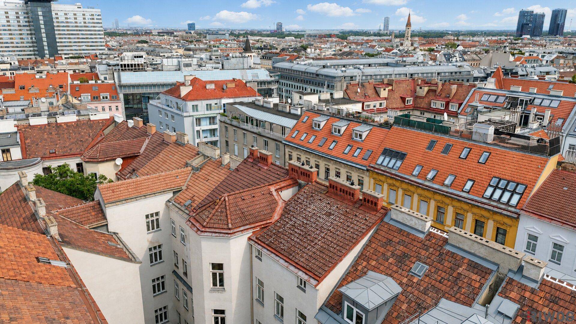 Panoramablick über die Dächer einer historischen Stadt mit modernen Gebäuden am Horizont.