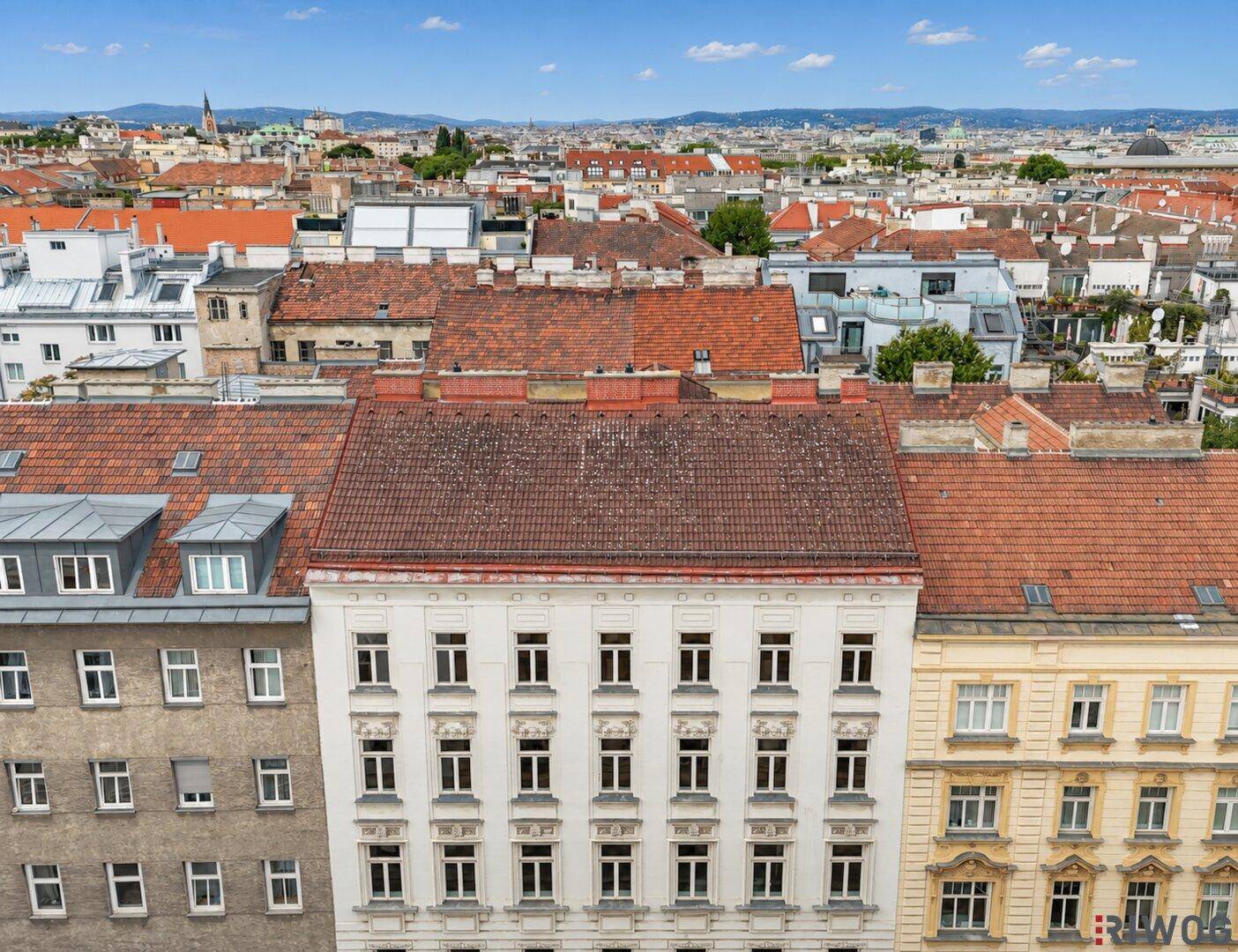 Fassadenansicht von Altbauten mit roten Ziegeldächern und Fenstern in einer Stadtlandschaft.
