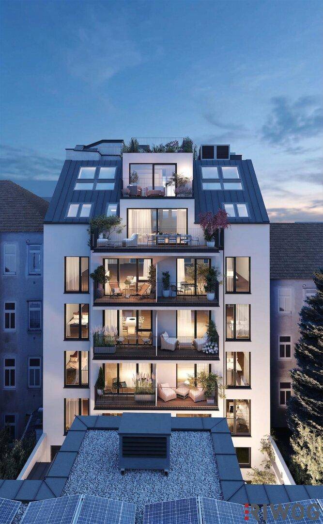 Modernes Wohngebäude bei Dämmerung mit beleuchteten Balkonen und Dachterrassen.