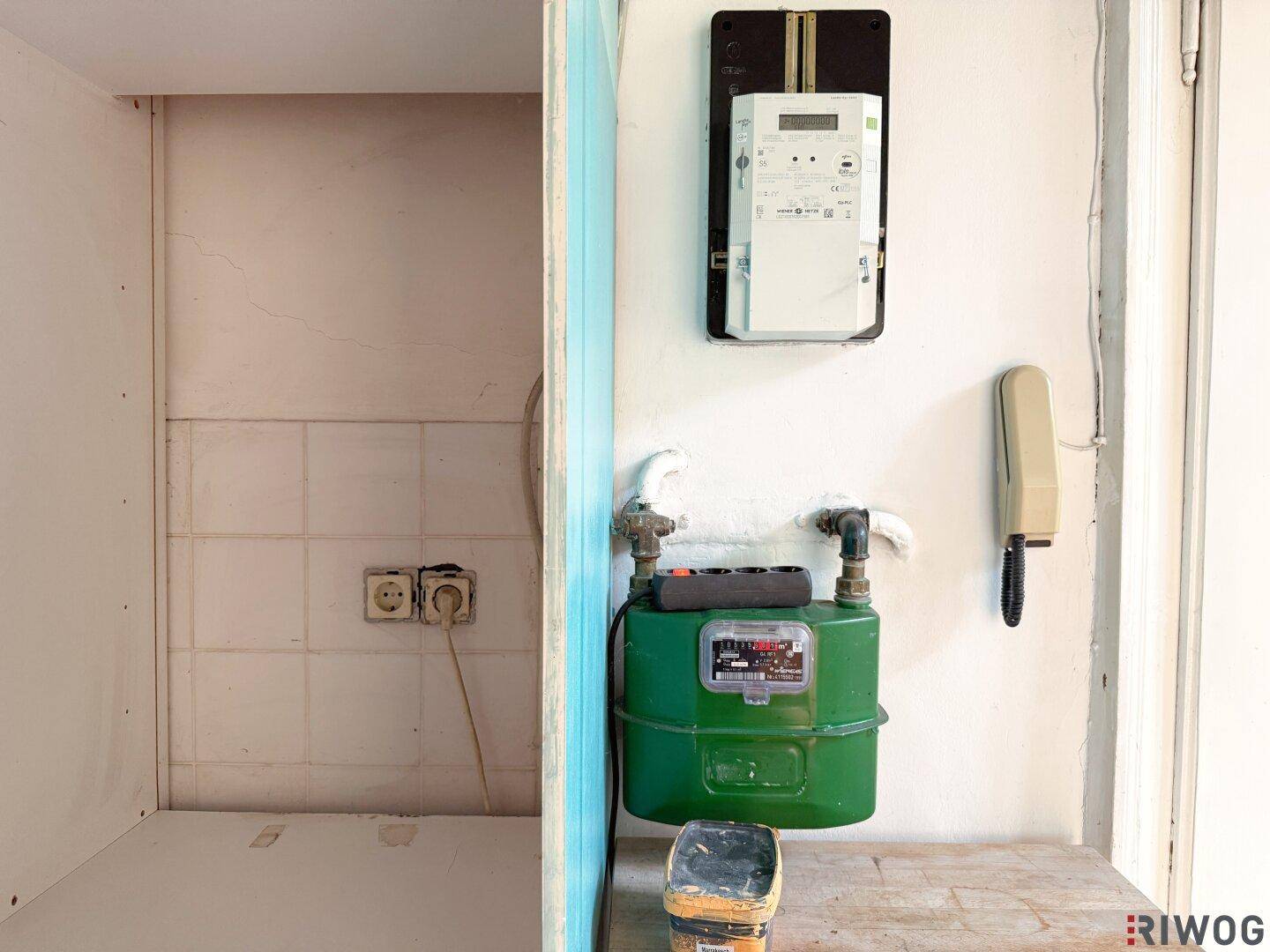 Bereich in der Küche mit Gaszähler, Stromzähler und Telefonanschluss an der Wand.