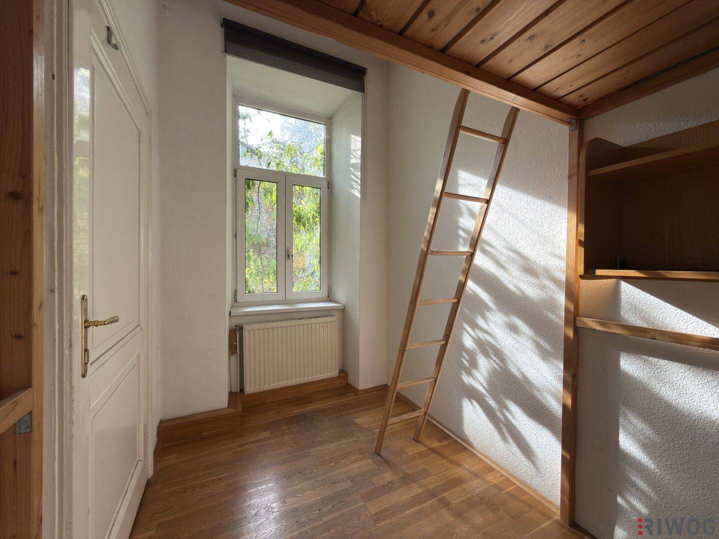 Schlafzimmer mit Holzboden, Fenster und Leiter zu einem Hochbett, das viel Licht erhält.