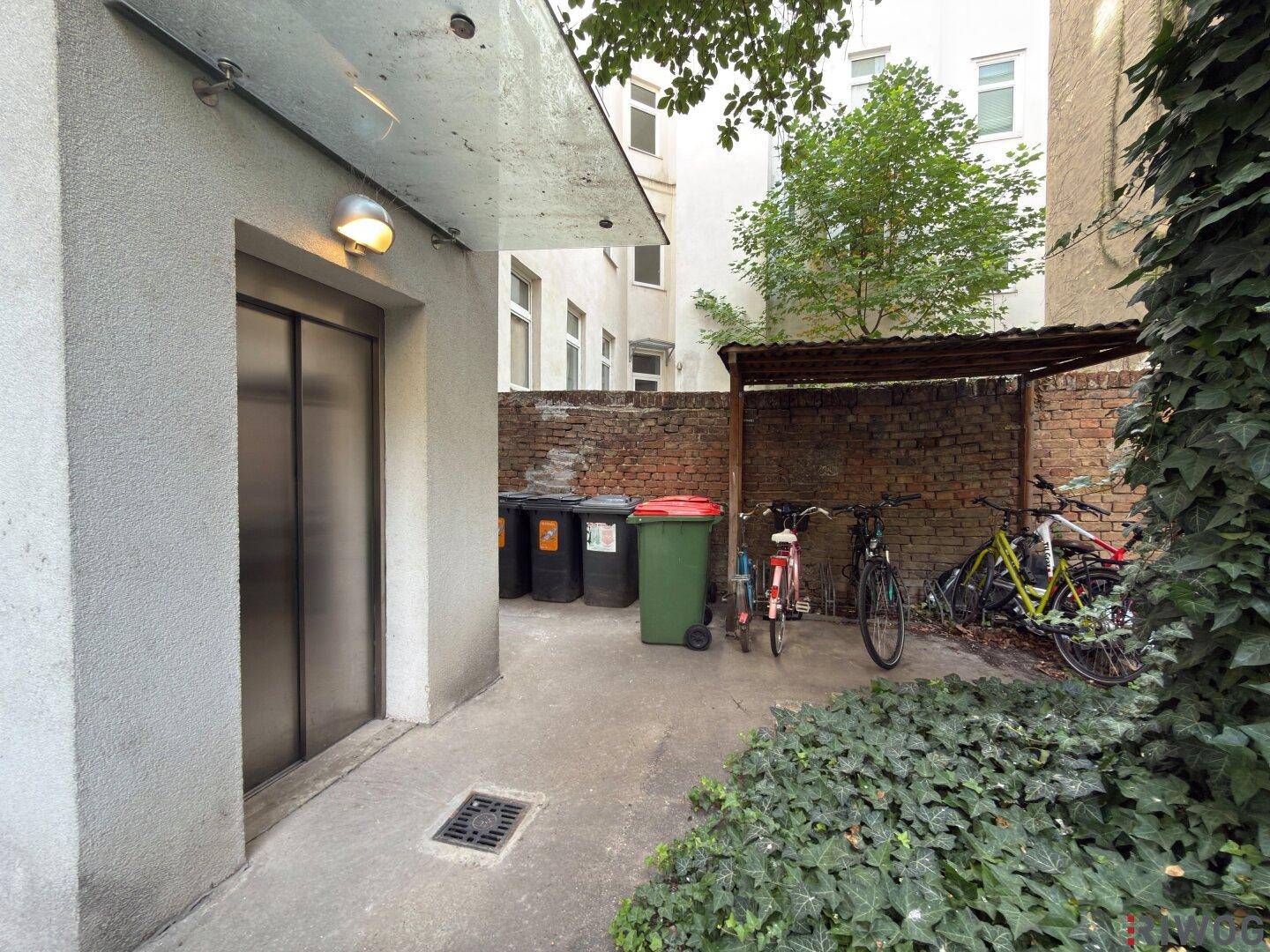 Innenhof mit Aufzugszugang, Fahrradabstellplatz und Mülltonnenbereich.