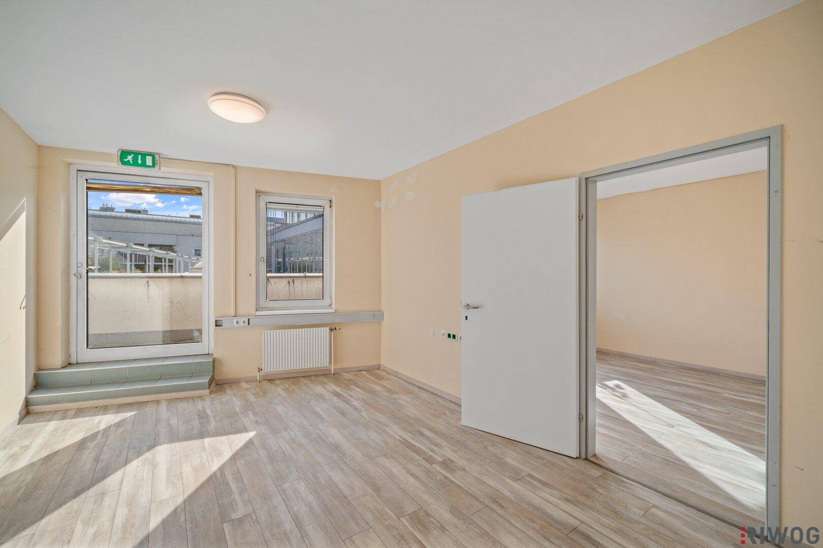 Heller Raum mit Zugang zu einem Balkon oder einer Terrasse und hellem Bodenbelag.