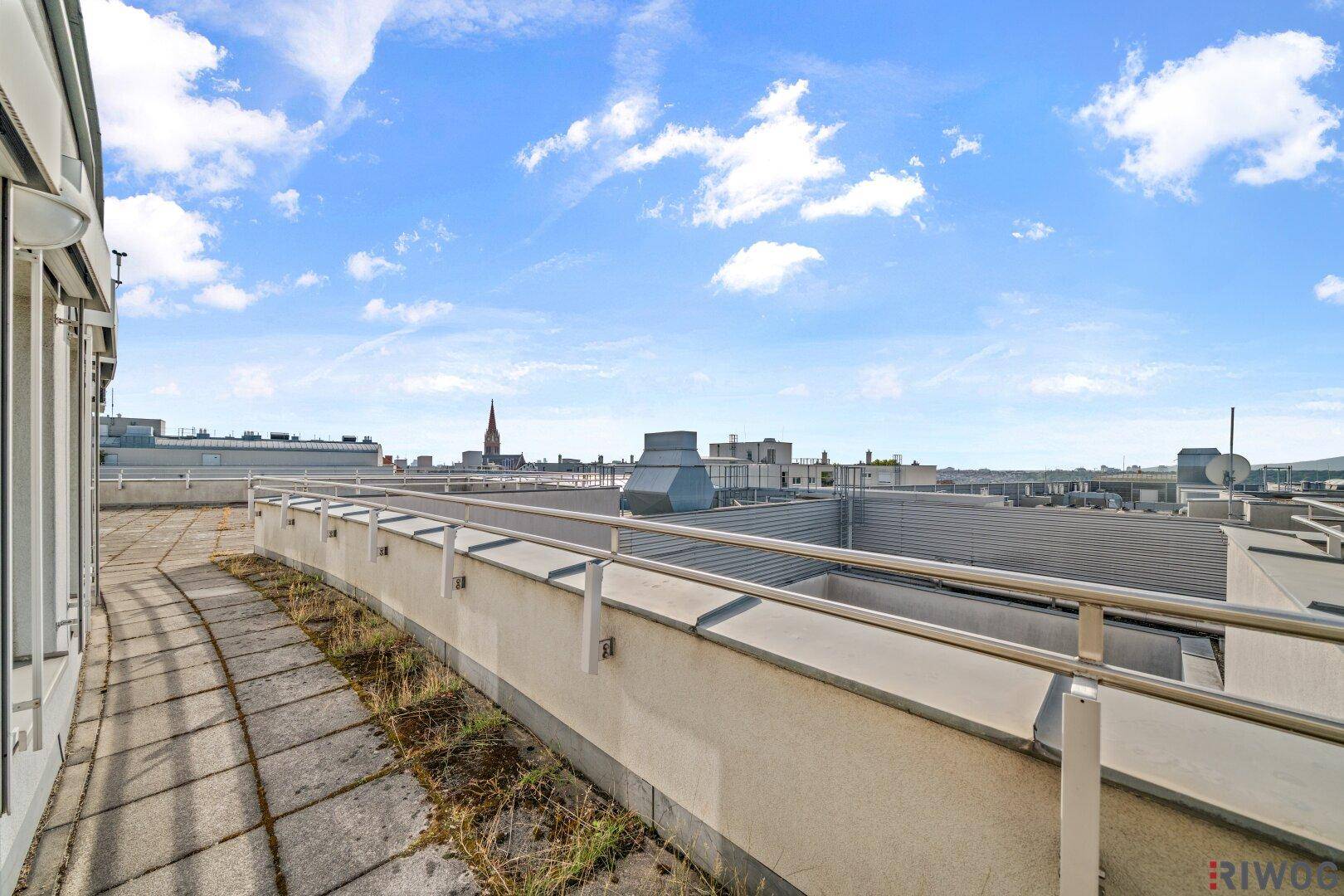 Schmaler Außenbereich mit Geländer und weitem Blick über die Dächer der Stadt.