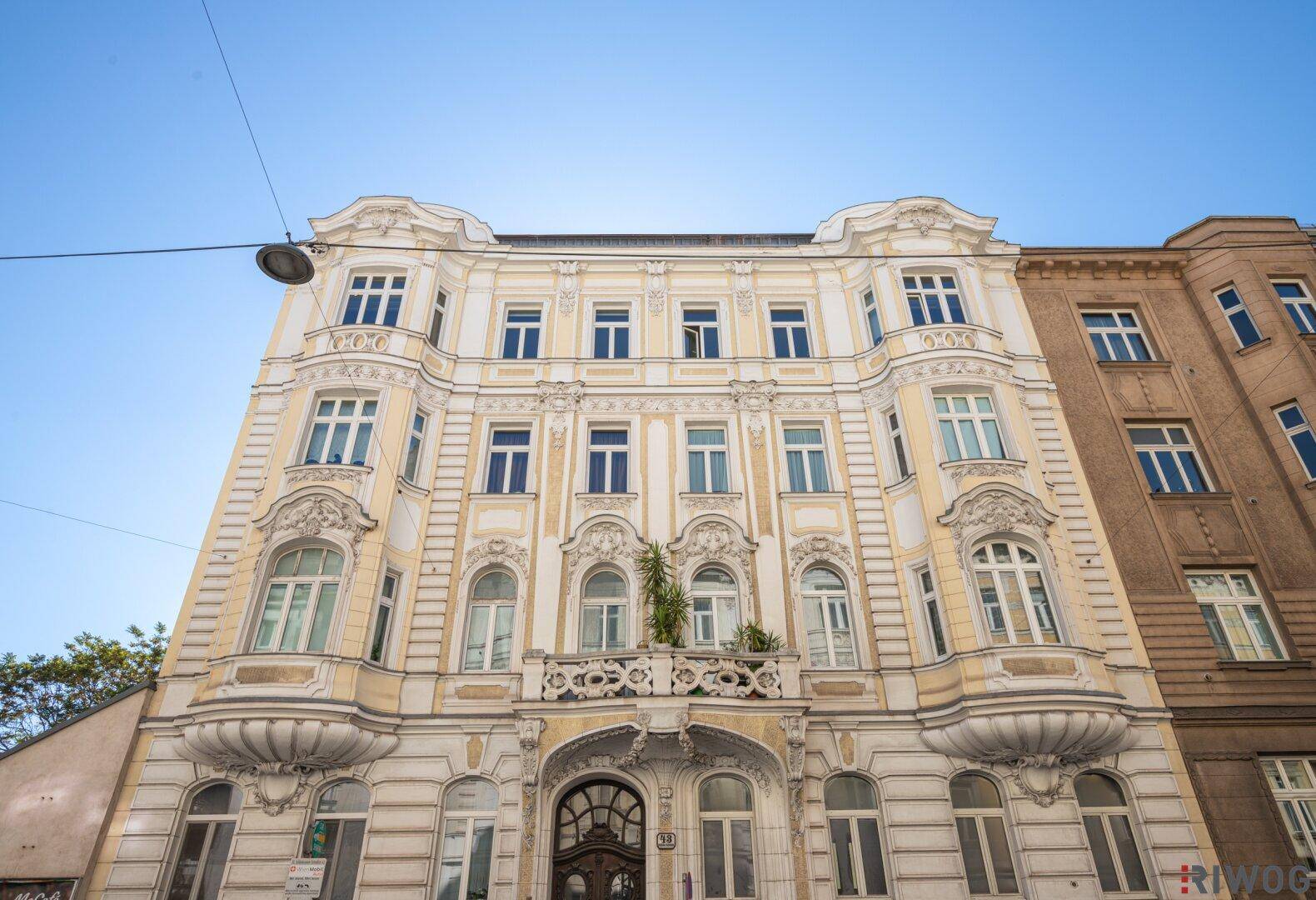 Historisches Gebäude mit detailreicher Fassade und vielen Fenstern, von unten fotografiert, in gutem Zustand.