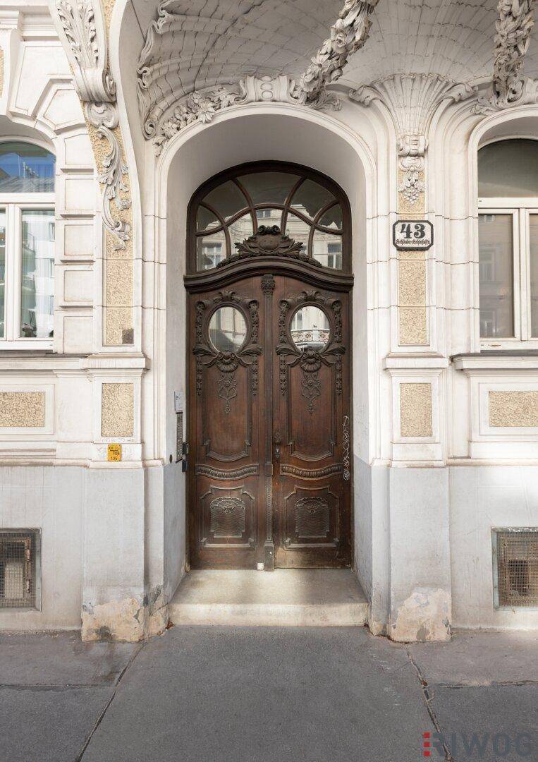 Detailaufnahme der kunstvoll geschnitzten Holztür des historischen Eingangs mit Hausnummer.