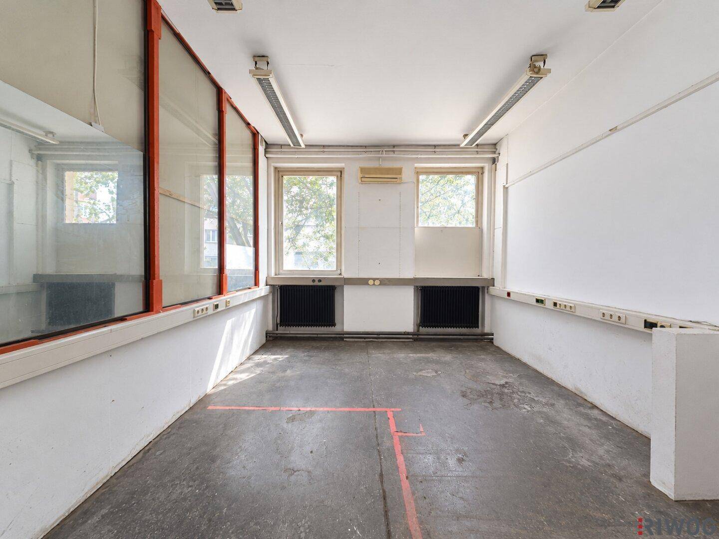 Funktionaler Büroraum mit zwei Fenstern, Heizkörpern und schlichten Wänden.
