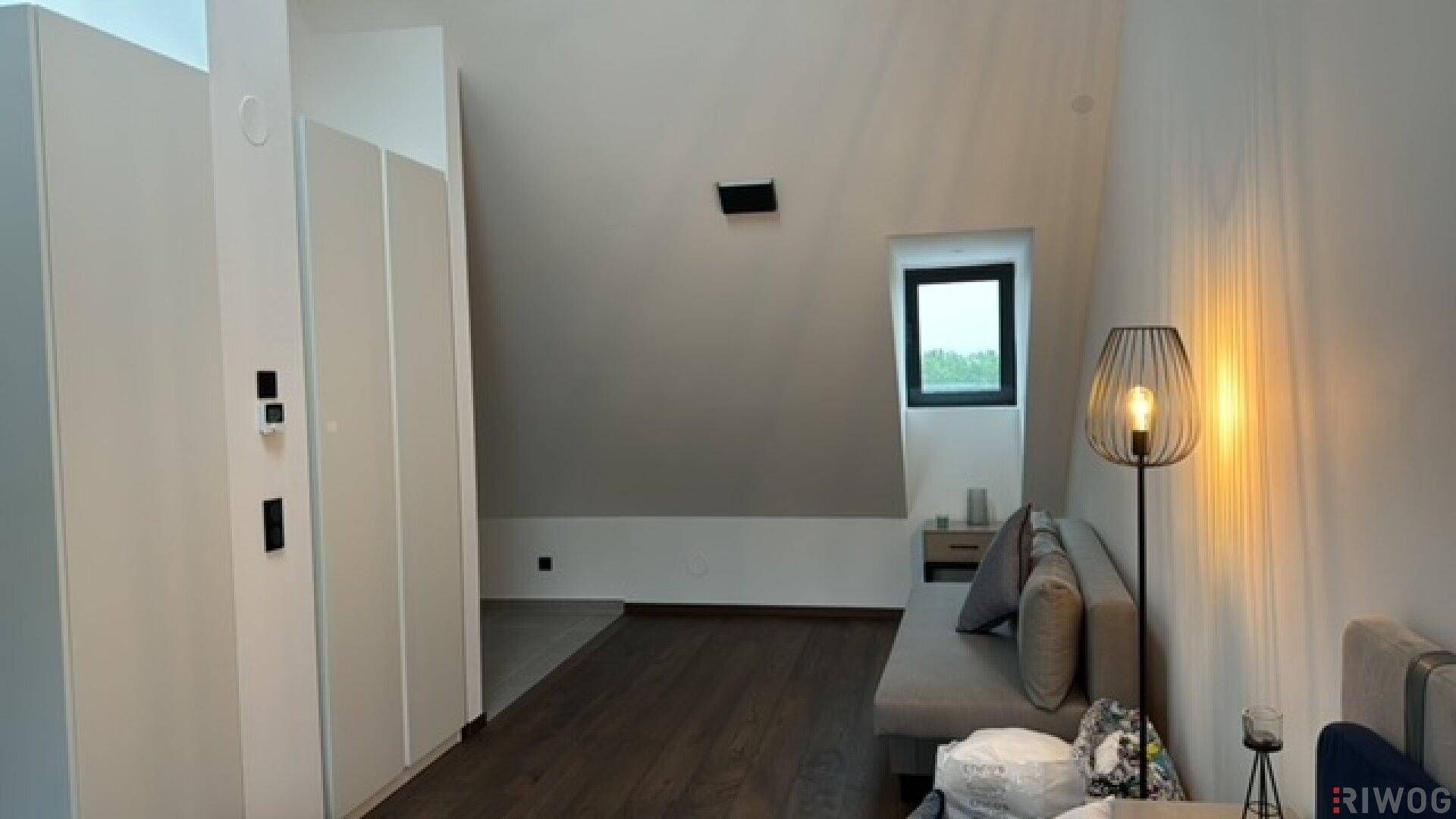 Gemütliches Schlafzimmer mit Dachschräge, Holzboden und integrierten Kleiderschränken.