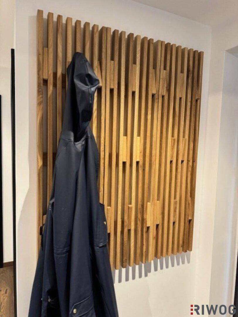 Moderner Flur mit dekorativer Holzlamellenwand und Garderobe.
