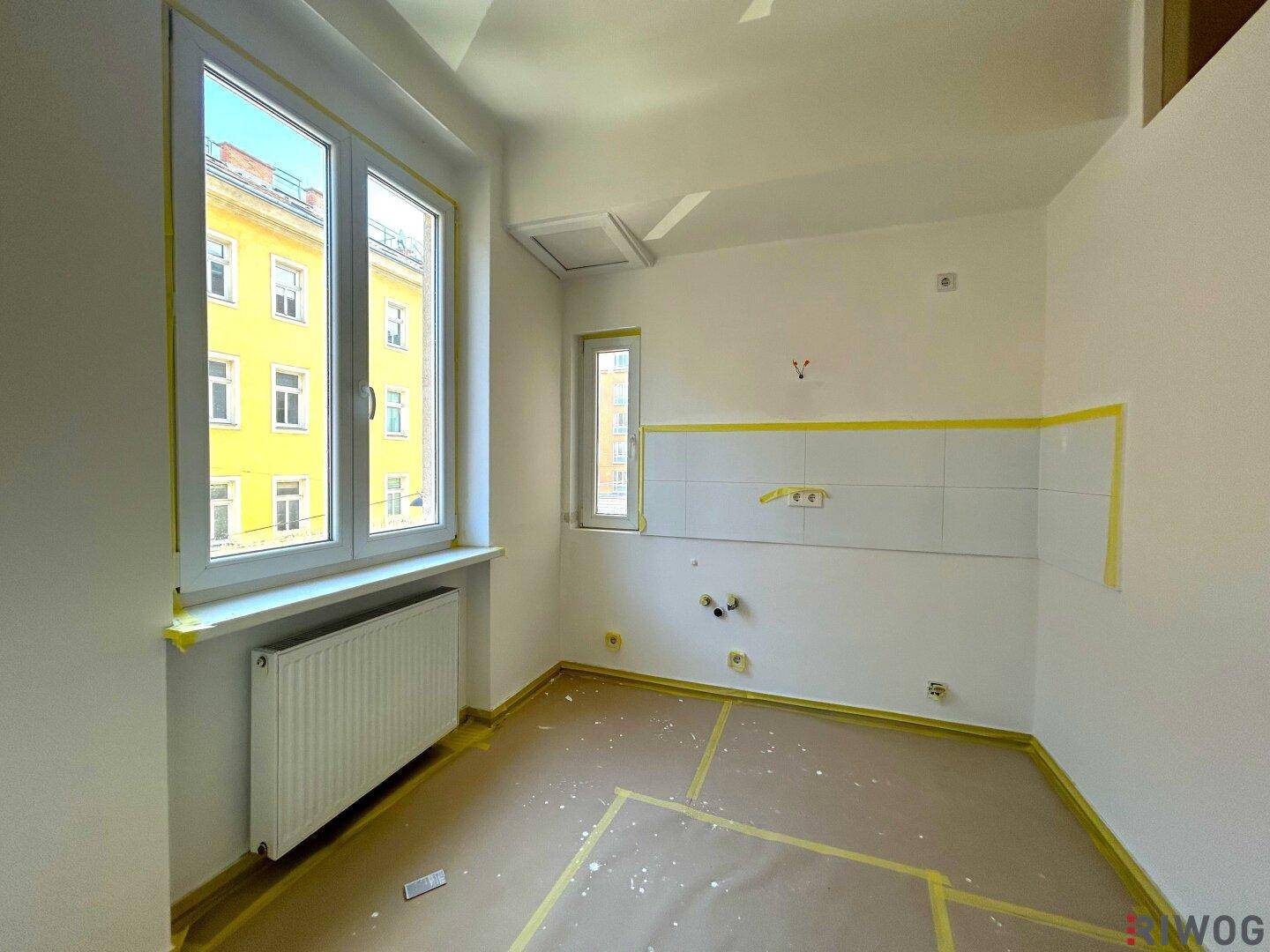 Küche im Renovierungszustand mit vorbereiteten Wänden und zwei Fenstern für gute Belüftung.