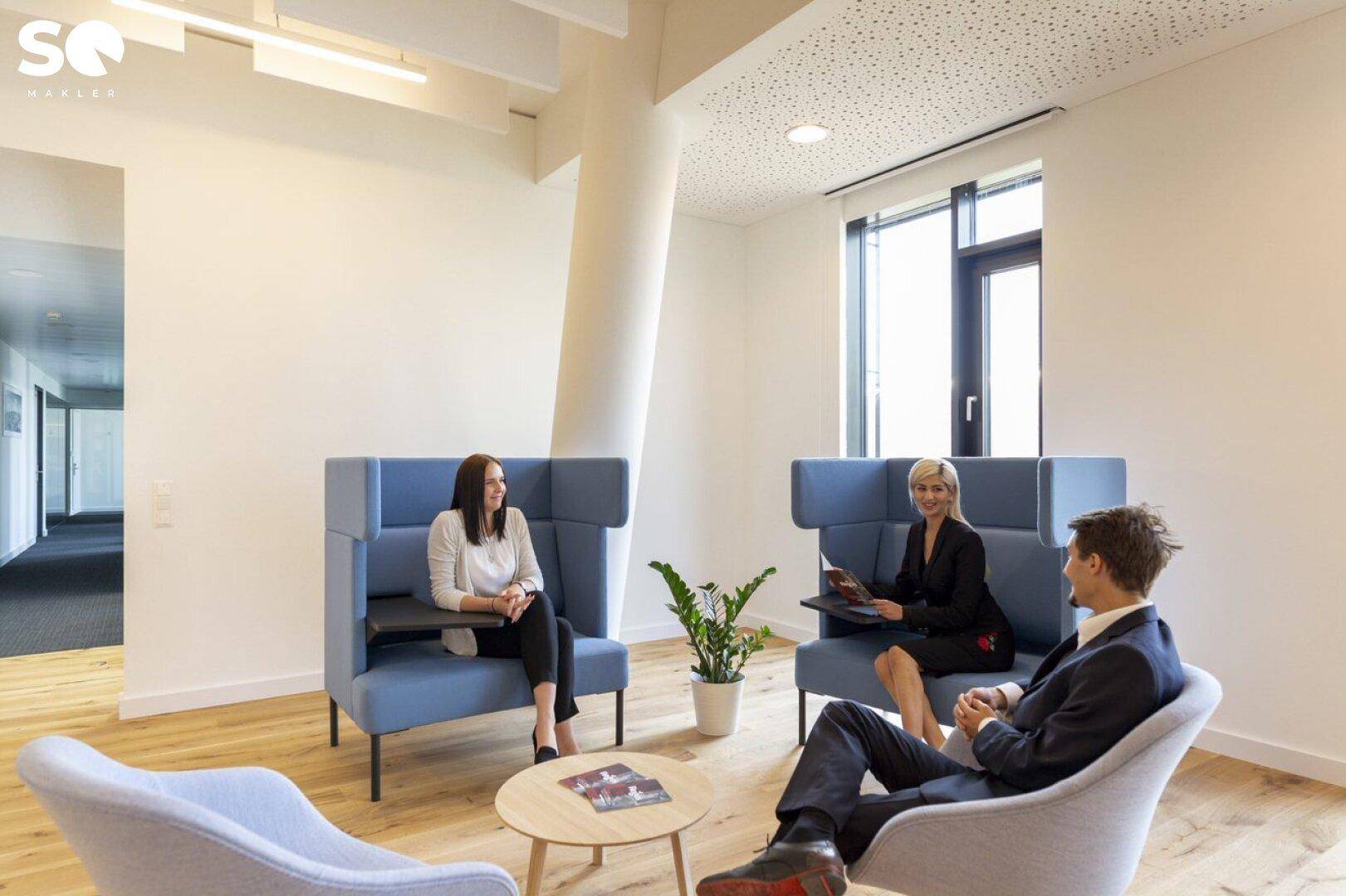 Komfortabler Loungebereich mit blauen Sitzgelegenheiten und Personen, die sich unterhalten.
