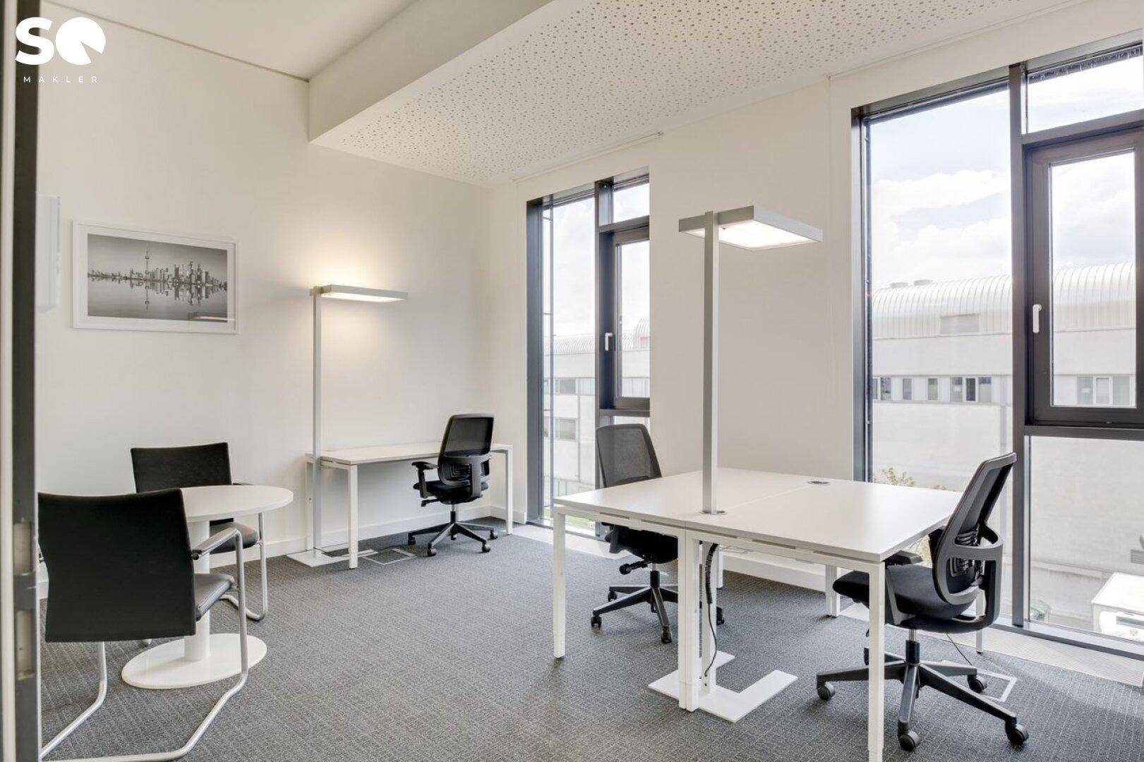 Helles Einzelbüro mit Schreibtischen, Bürostühlen und Teppichboden.