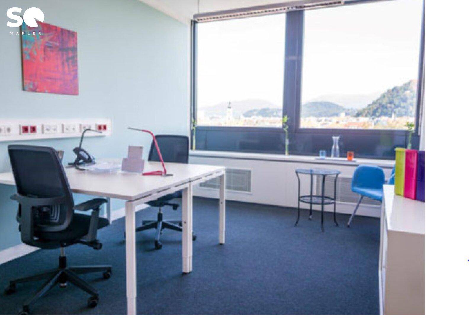 Helles Einzelbüro mit weitem Blick auf die Stadt und die umliegende Landschaft durch große Fenster.