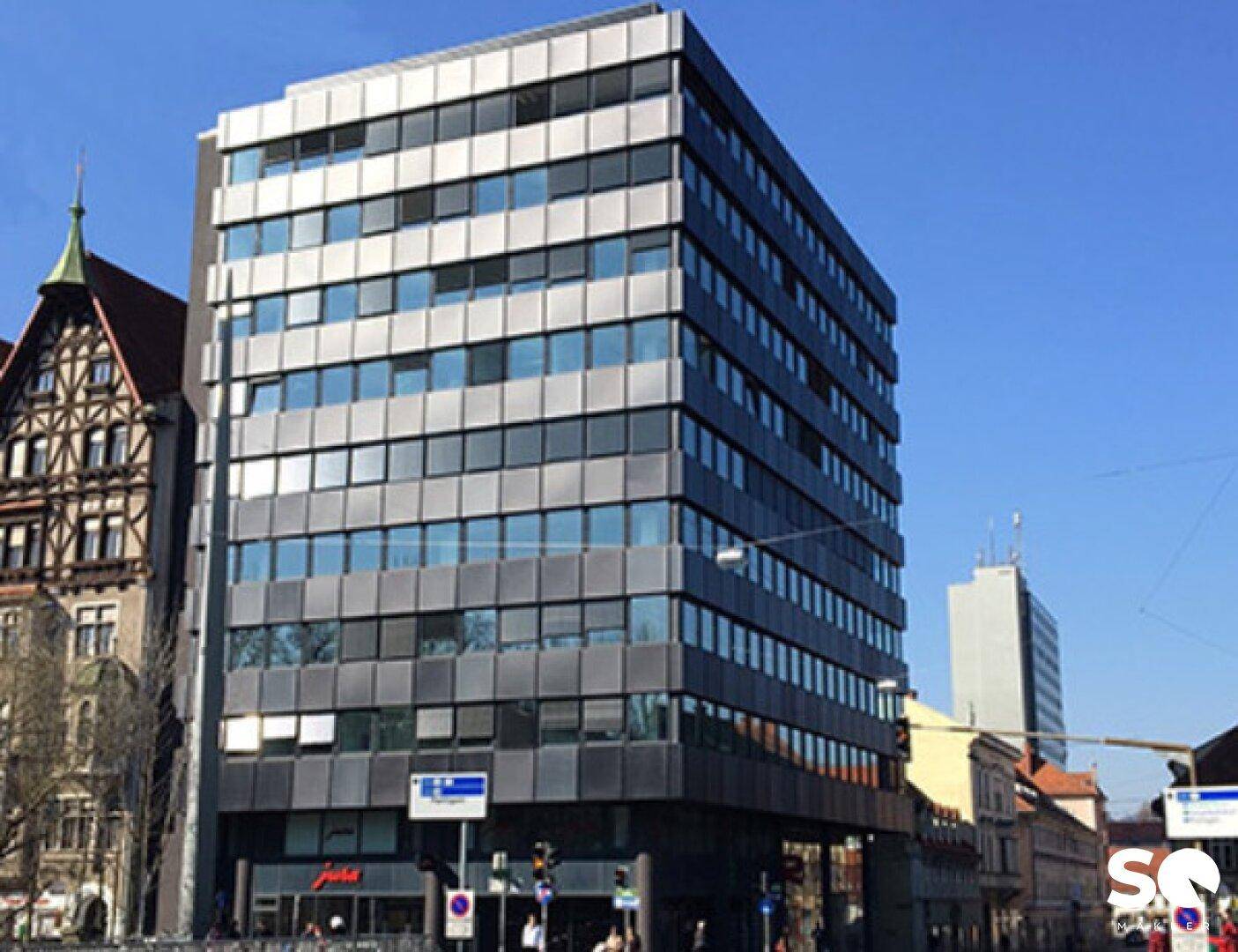 Zeitgenössisches Bürogebäude mit markanter Glas- und Metallfassade in urbaner Umgebung.