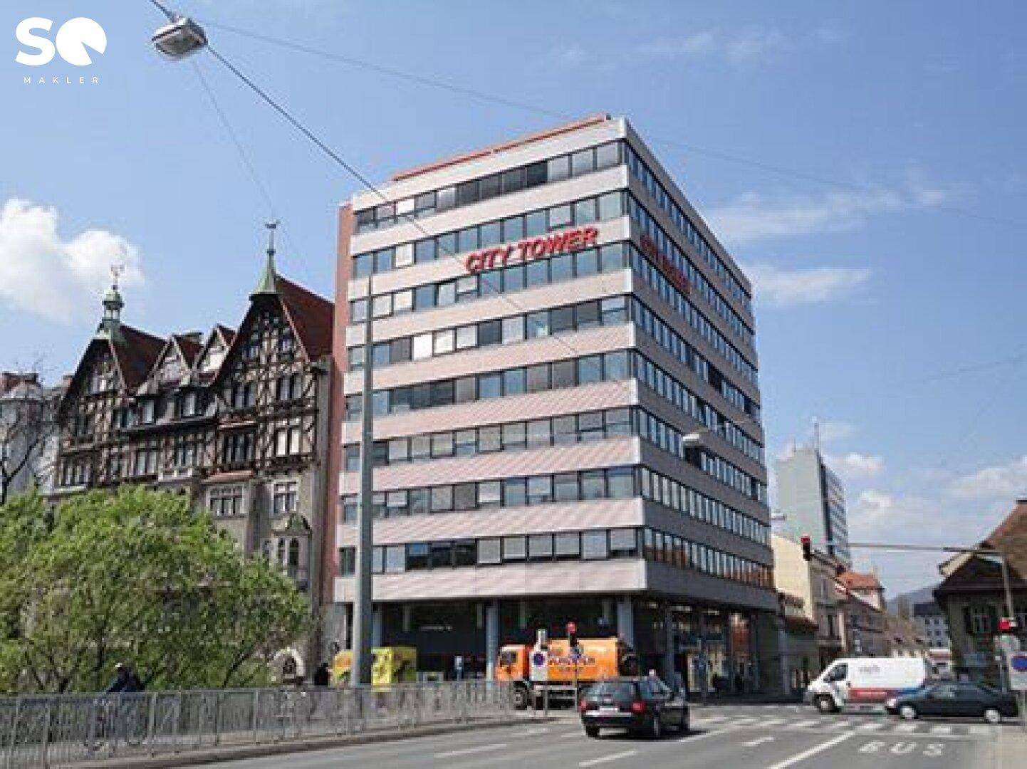 Modernes Bürogebäude "City Tower" mit vielen Fenstern und traditioneller Architektur im Hintergrund.