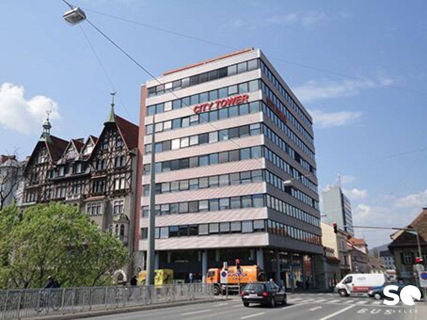 Modernes Bürogebäude "City Tower" an einer belebten Straße mit umliegender Architektur.