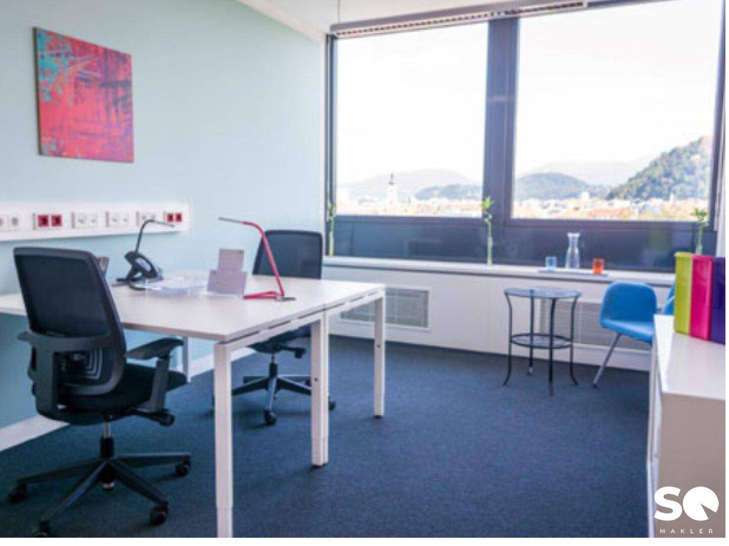 Ruhiges Büro mit Schreibtisch, Stuhl und einem weiten Blick auf die umliegende Berglandschaft.