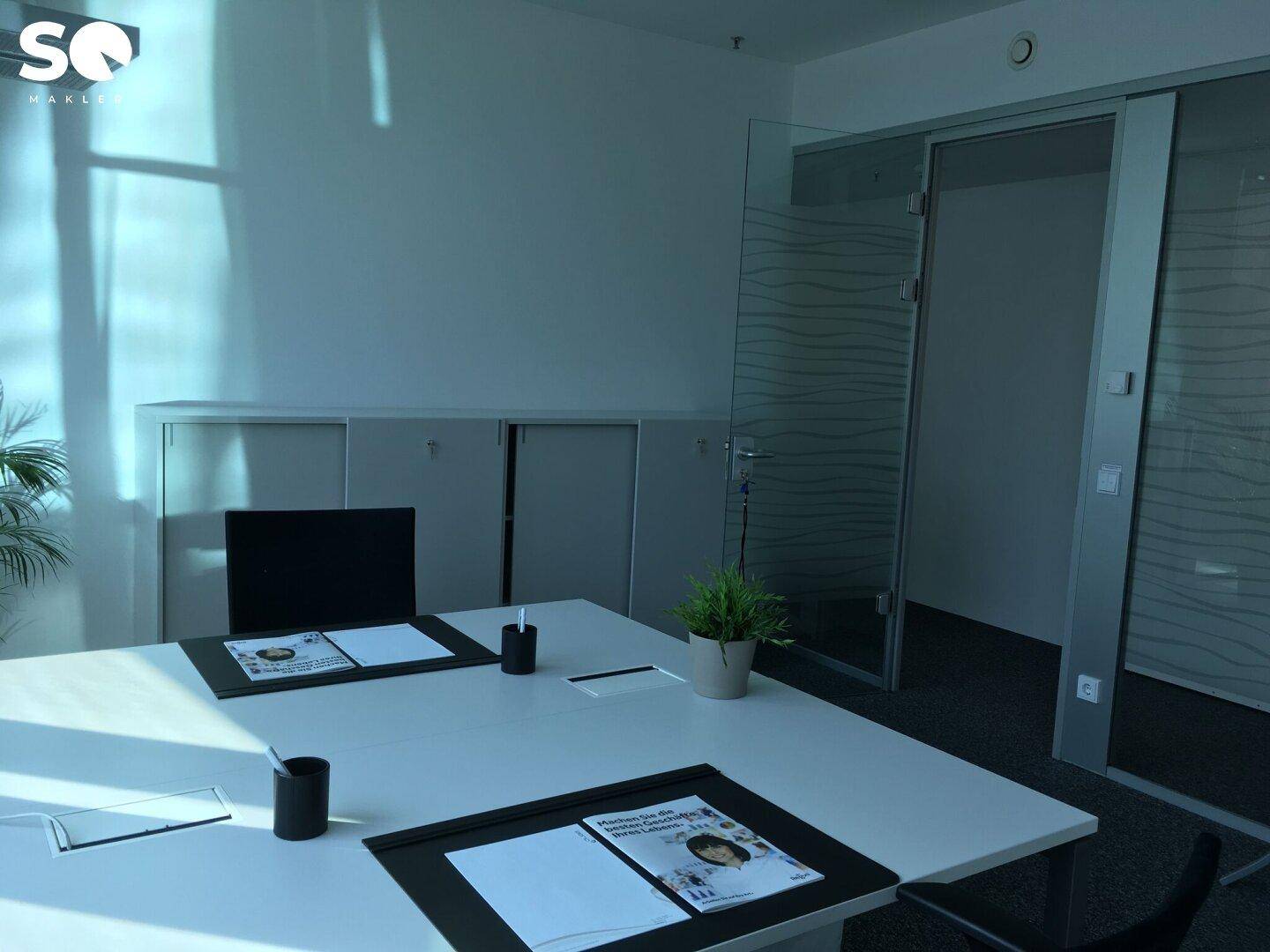 Modernes Einzelbüro mit Schreibtisch, Stauraum und einer eleganten Glasschiebetür.