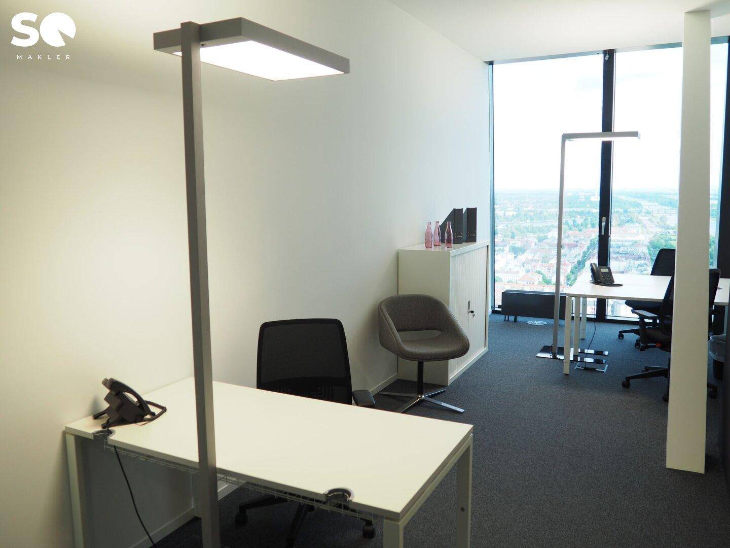 Helles Einzelbüro mit Schreibtisch, Bürostuhl und großem Fenster, das viel Tageslicht hereinlässt.