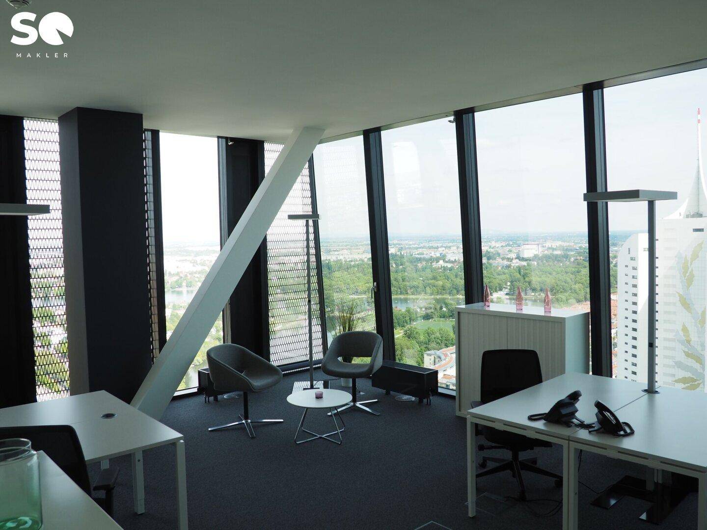 Großzügiger Bürobereich mit raumhohen Fenstern, modernen Möbeln und weitem Blick über die Stadt.