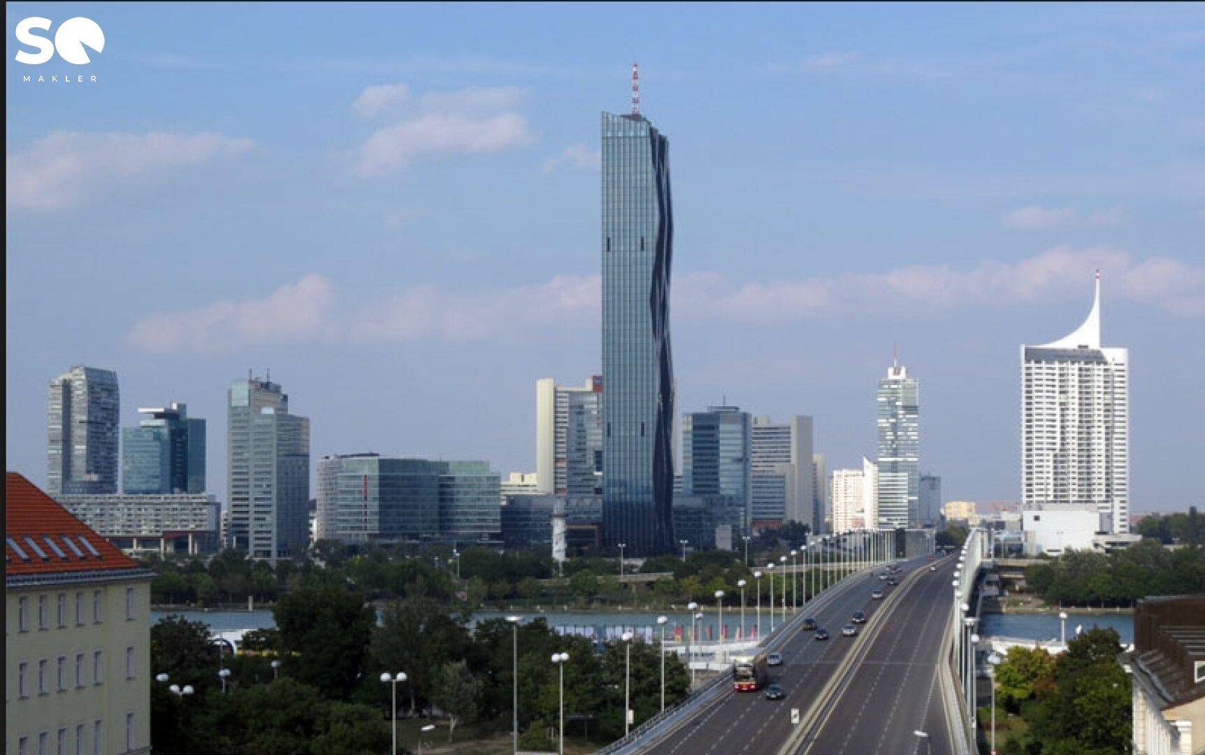 Panoramablick auf eine moderne Stadtlandschaft mit Hochhäusern, Brücke und Fluss unter blauem Himmel.