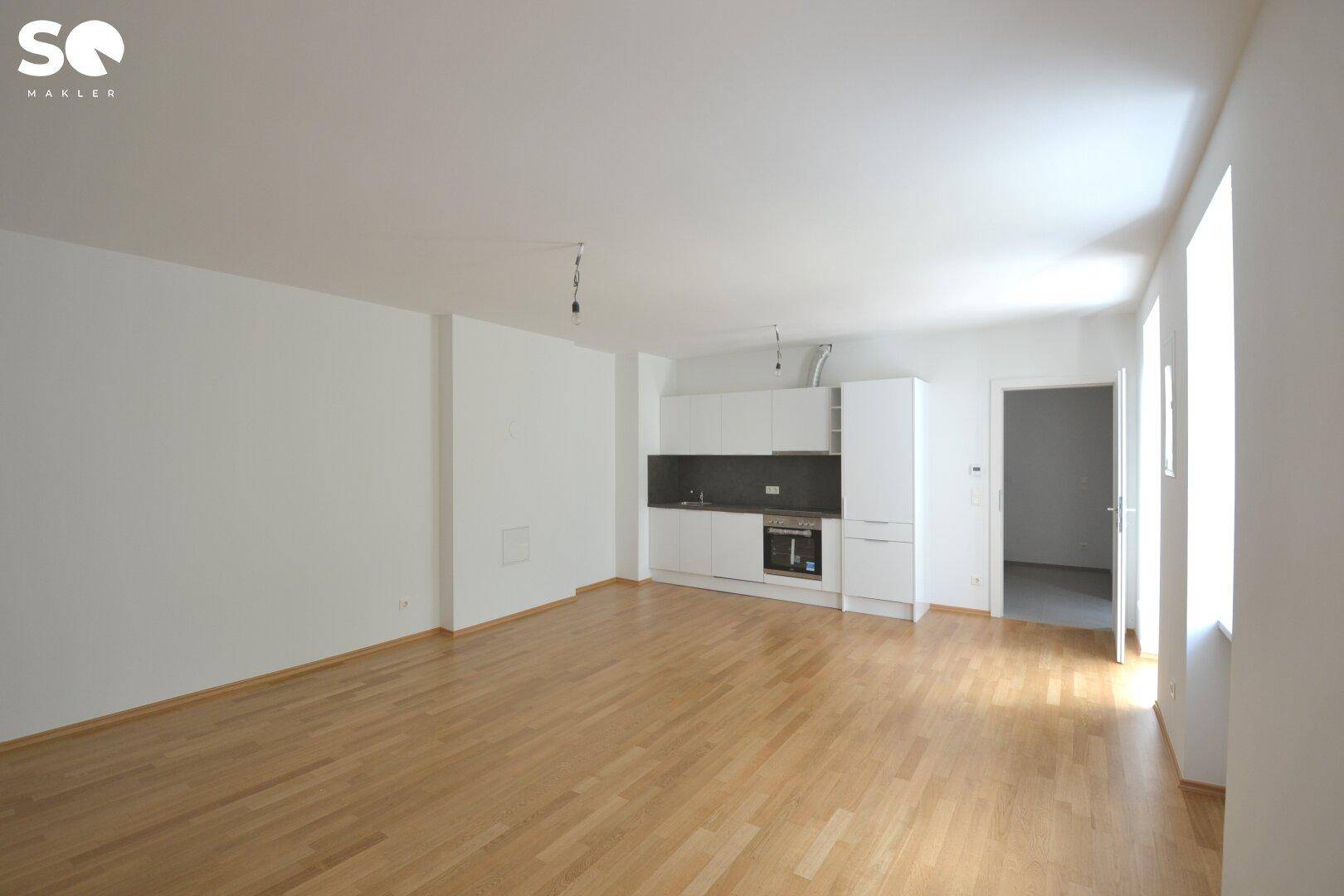 Geräumiger Wohnbereich mit heller Küchenzeile und Eichenparkett, ideal für offenes Wohnen.