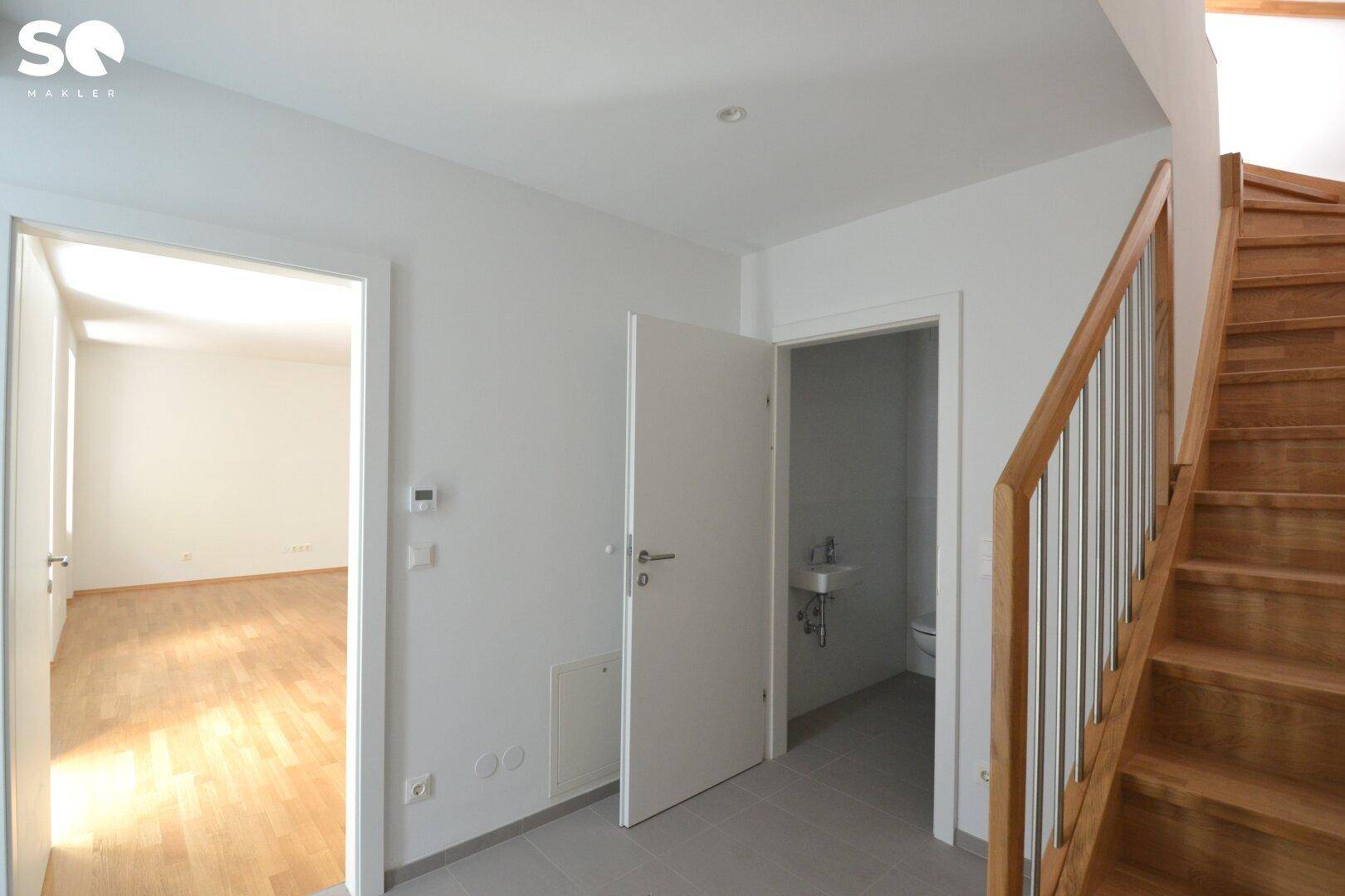Flur mit Holztreppe und Zugang zu einem weiteren Zimmer sowie einem Gäste-WC.