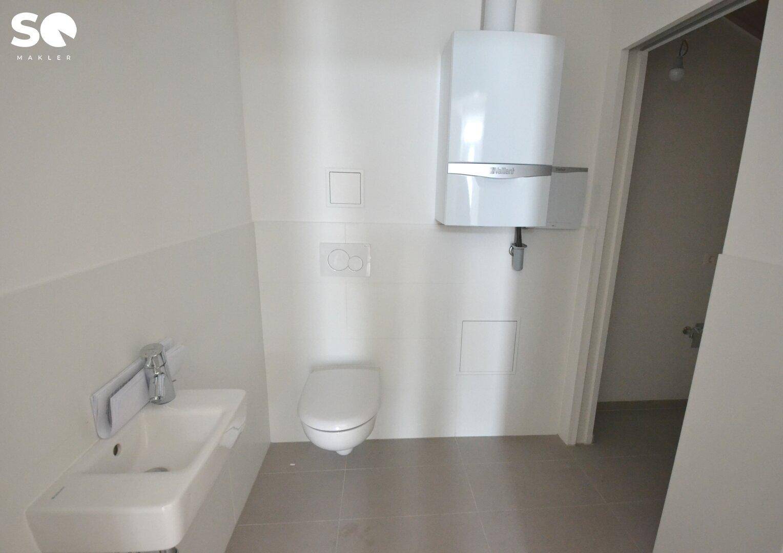 Modernes Gäste-WC mit wandhängendem WC, kleinem Waschbecken und Gastherme.