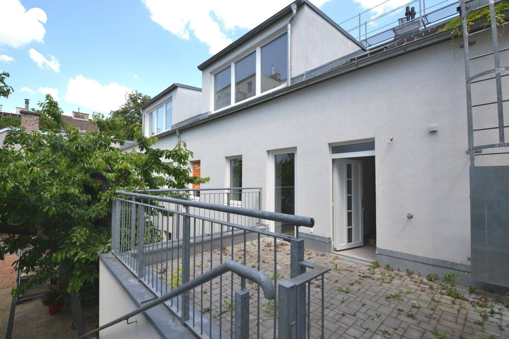 Außenansicht des Gebäudes mit Terrasse, Außentreppe und Blick auf die Umgebung.