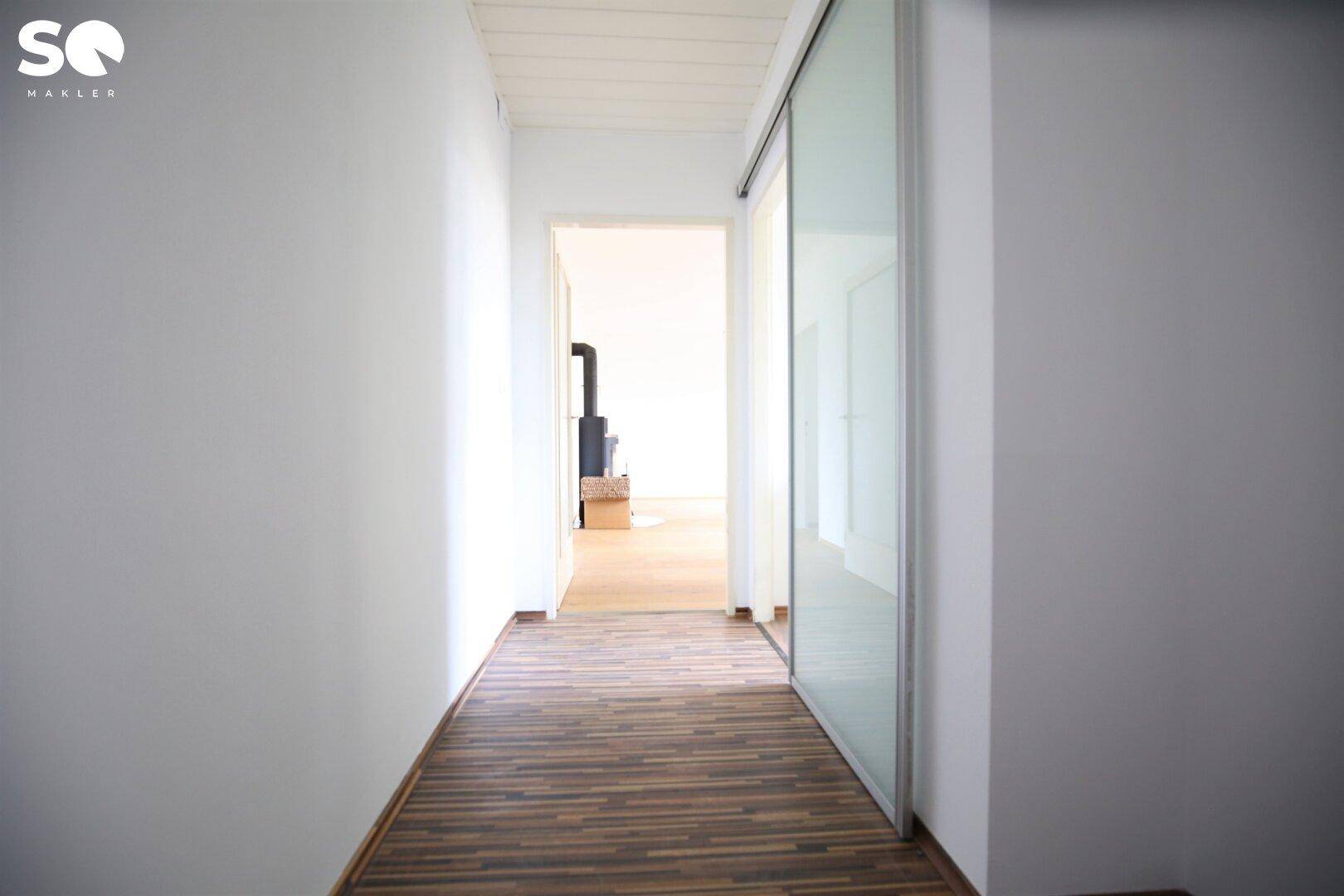 Heller Flur mit Laminatboden und moderner Glasschiebetür.