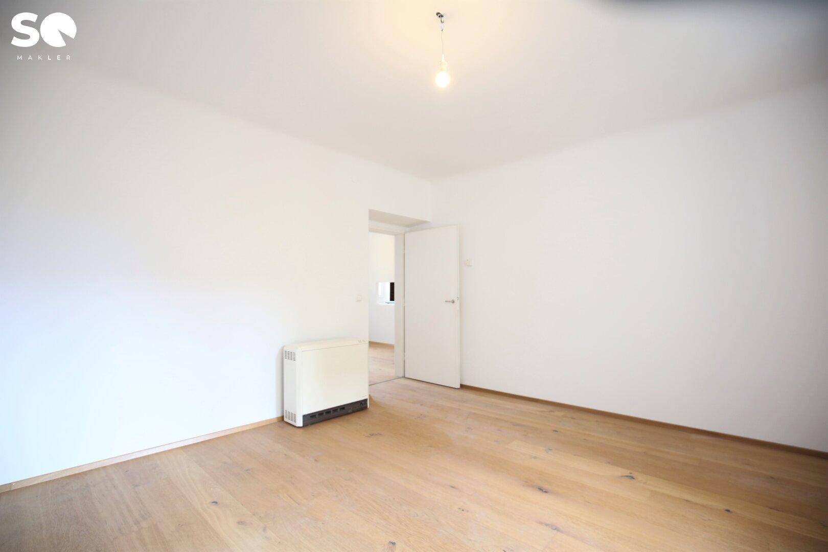 Geräumiges Schlafzimmer mit Holzboden und Heizkörper.