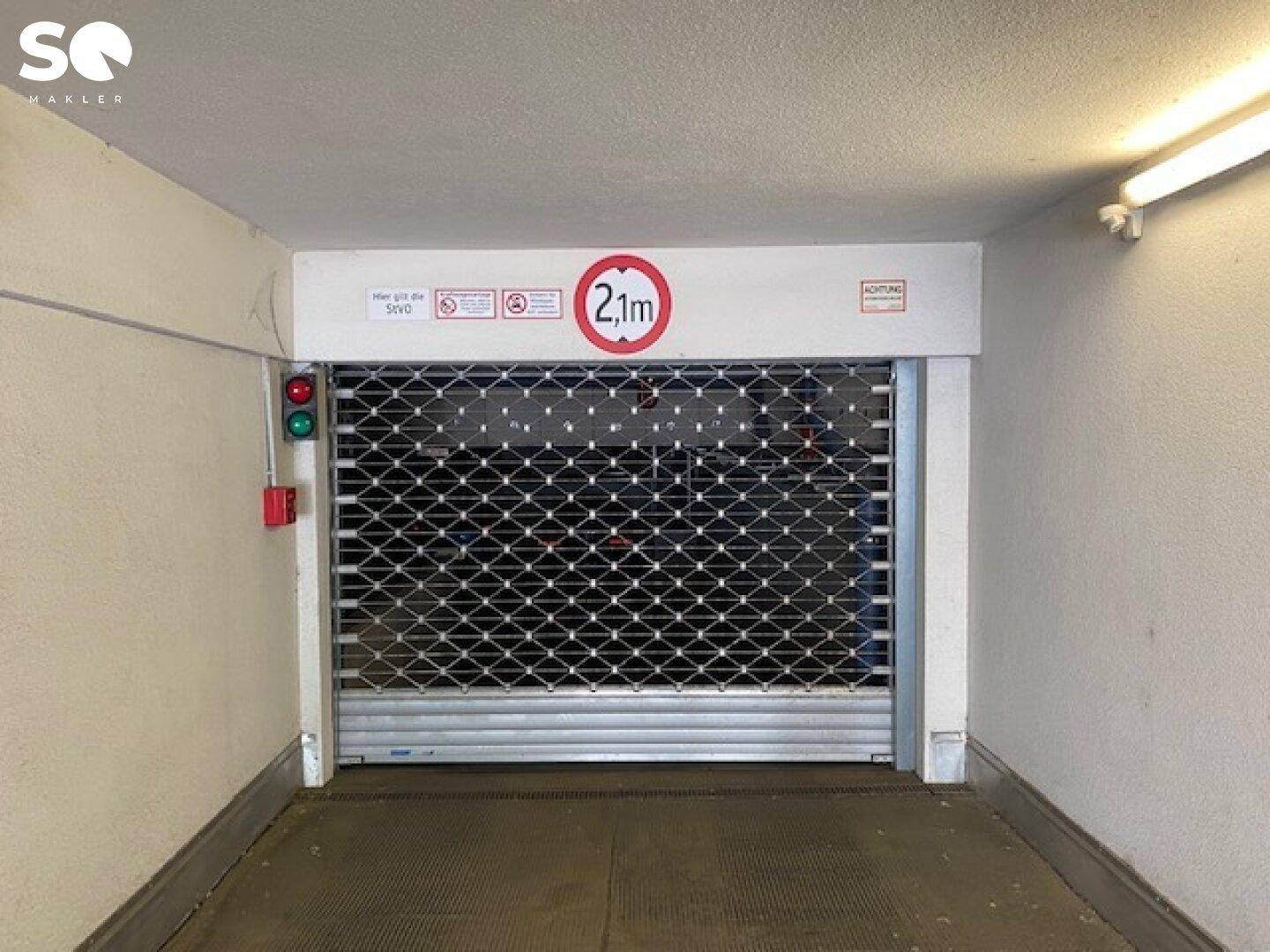 Einfahrt zu einer Tiefgarage mit Rolltor und Höhenbegrenzung von 2,1 Metern.