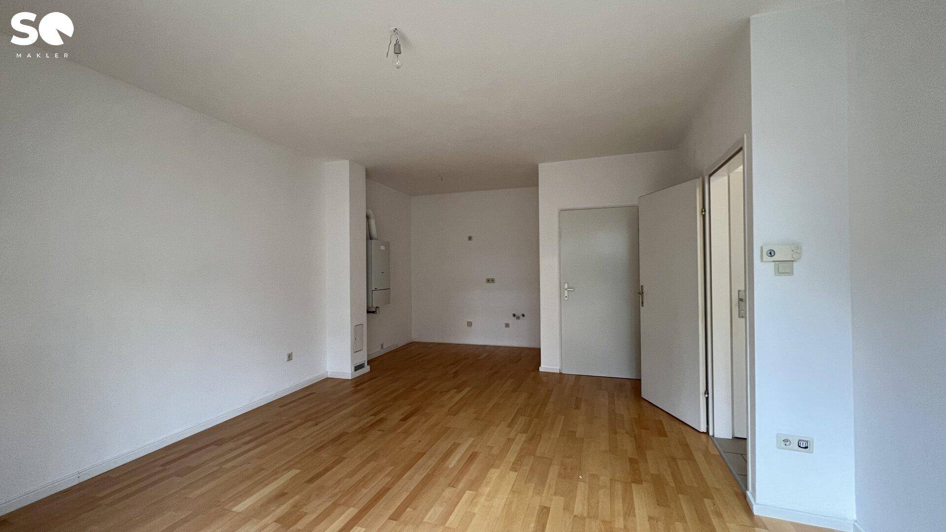 Großer, heller Raum mit Holzfußboden und weiß gestrichenen Wänden, bereit zur Einrichtung.