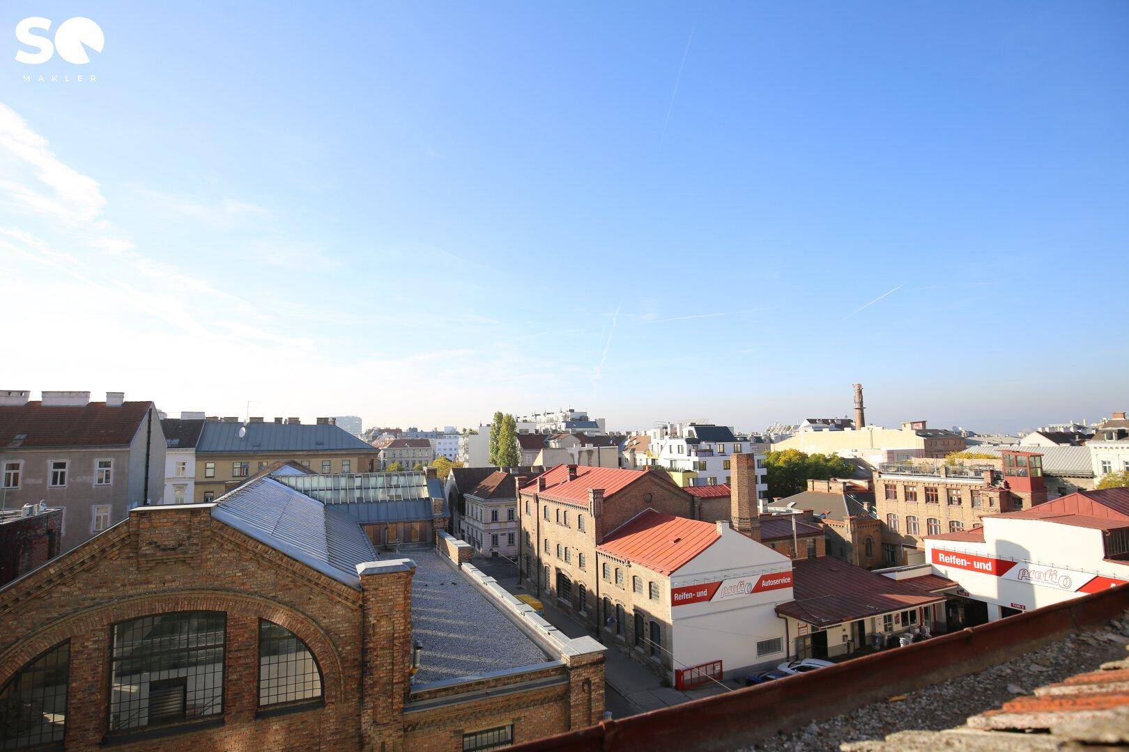 Panoramablick über die Dächer der Stadt mit verschiedenen Gebäudetypen und klarem Himmel.