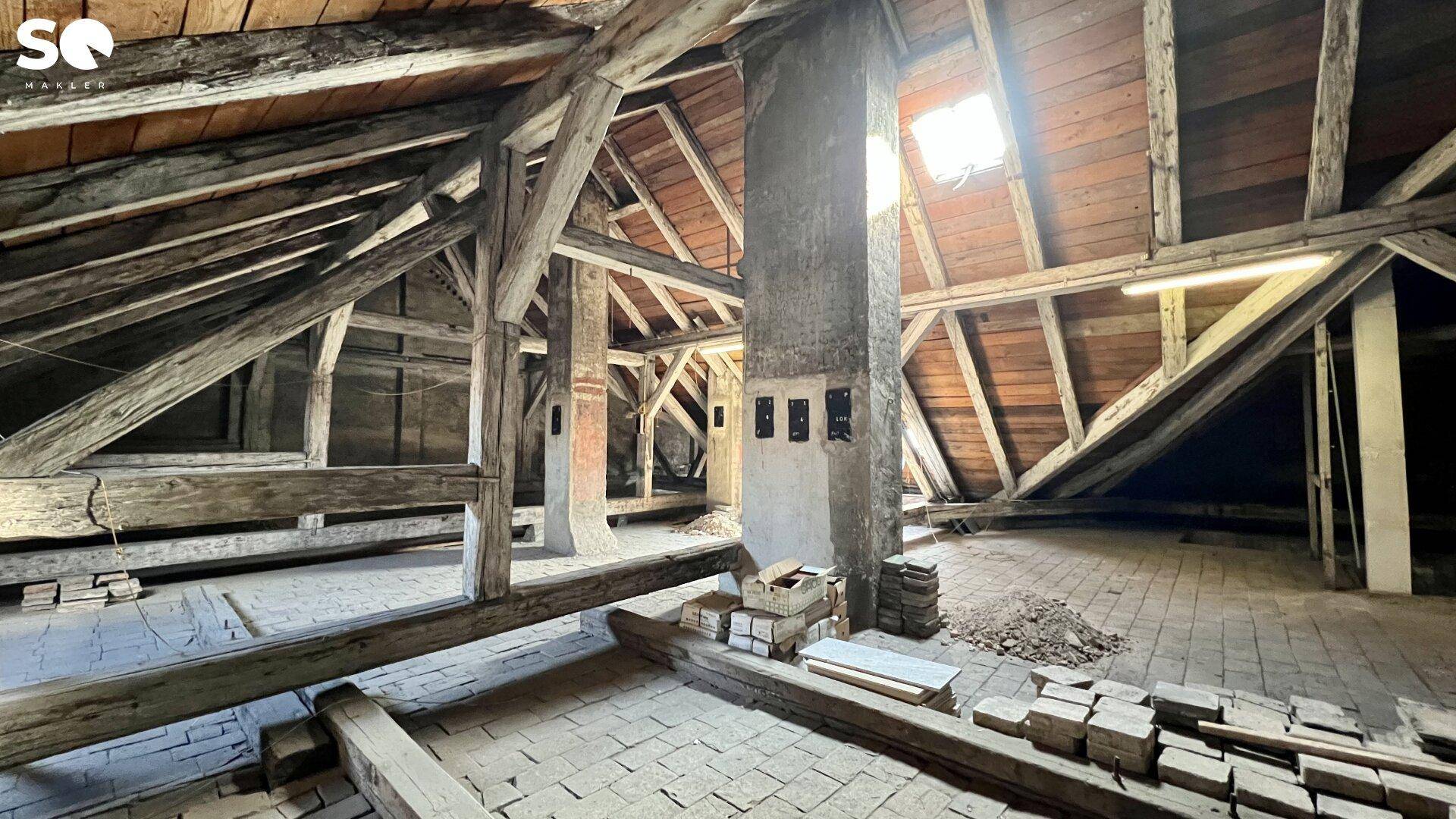 Geräumiger Dachboden mit sichtbaren Holzbalken und einem Dachfenster, bereit für den Ausbau.