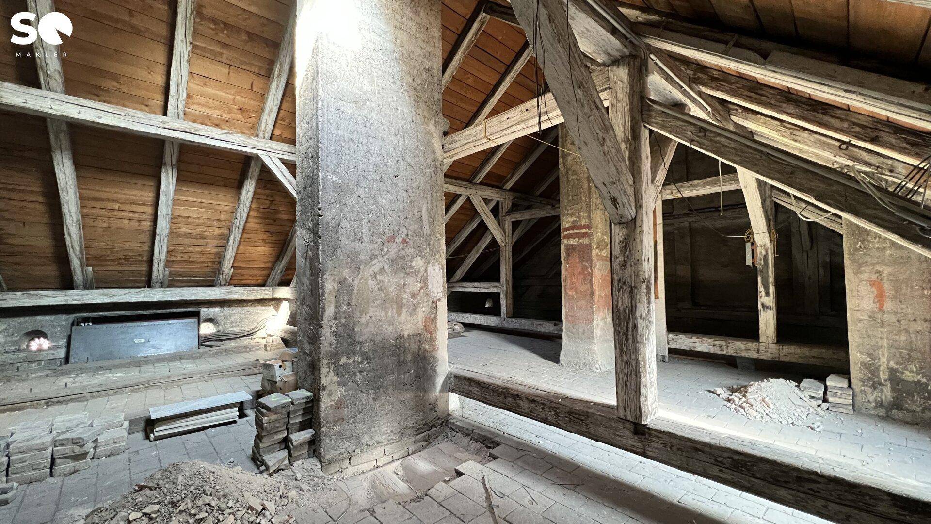 Dachbodenbereich mit massiven Holzbalken und einem gemauerten Kaminzug, viel Potenzial.