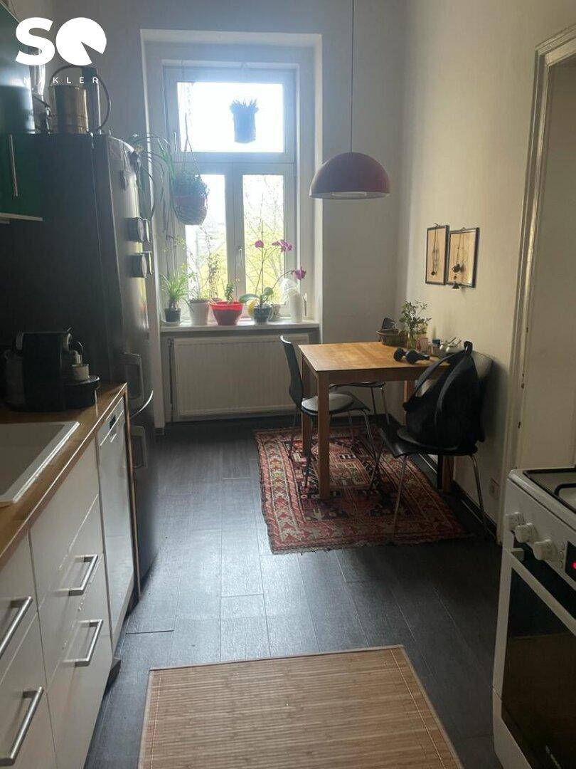 Funktionale Küche mit Essbereich, Fenster und dunklem Boden, ausgestattet mit grundlegenden Geräten.