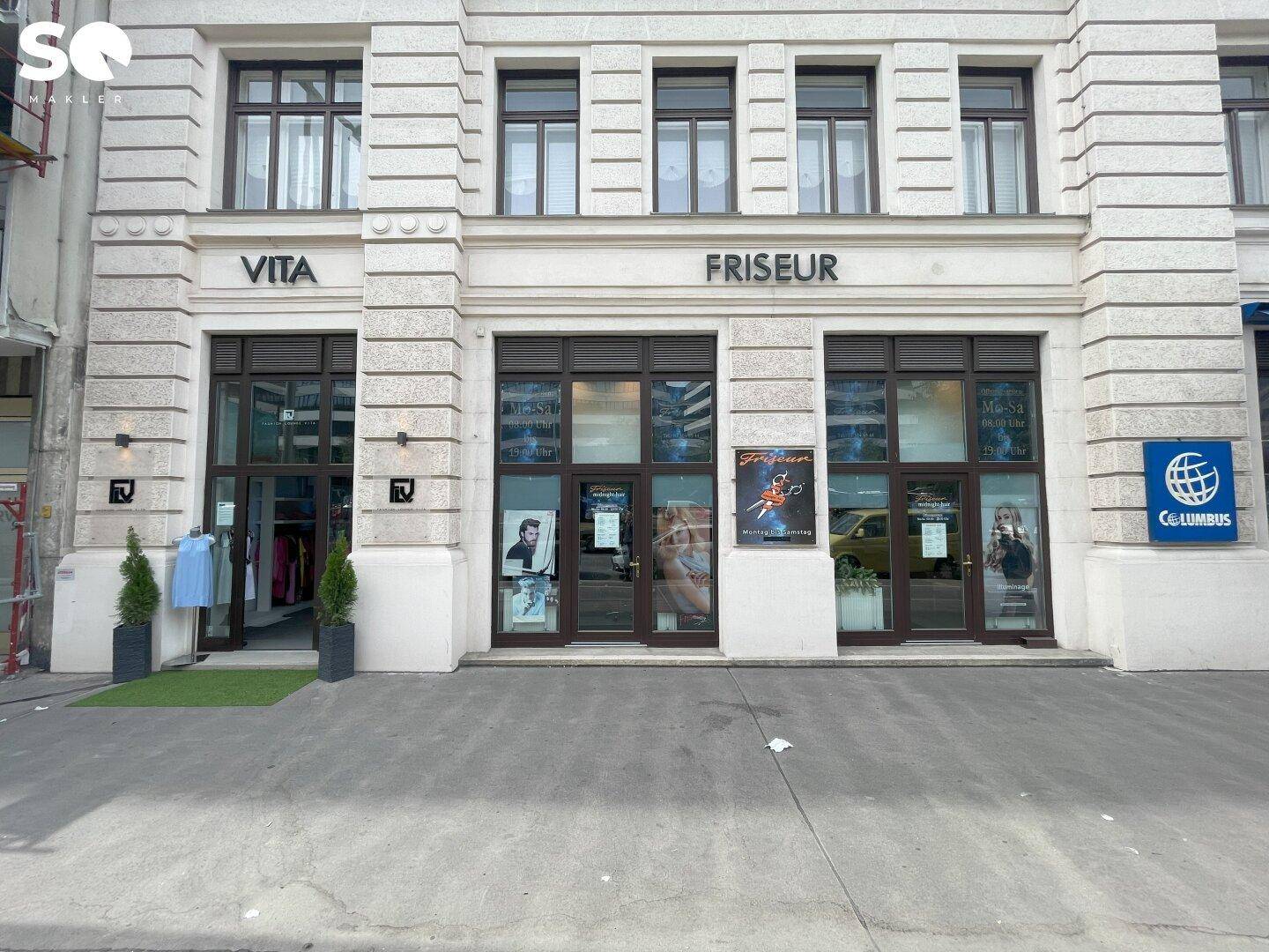Detailansicht der Ladenfronten eines Friseursalons und einer Boutique in einem klassischen Gebäude.