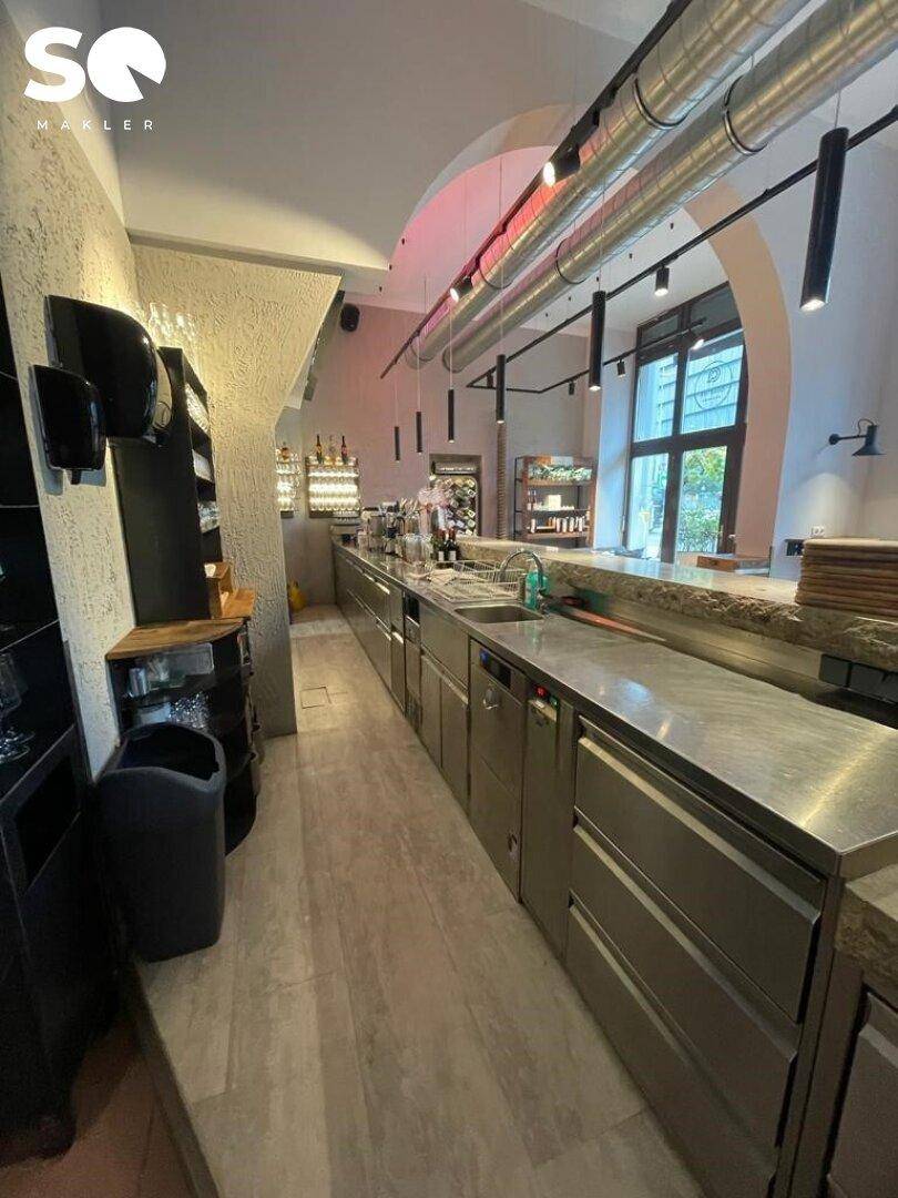 Professionelle Küche mit langen Edelstahltheken und integrierten Geräten, bereit für den Gastronomiebetrieb.