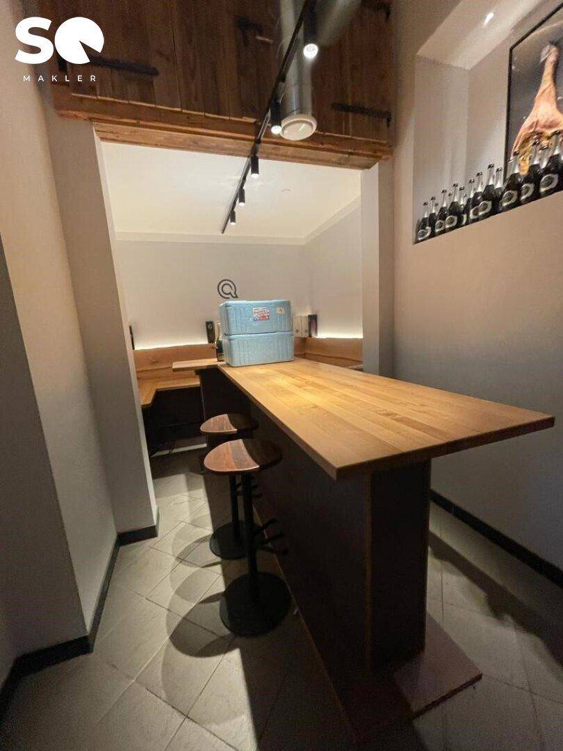 Gemütlicher Sitzbereich mit Holztisch, Barhockern und eingebauten Holzbänken, ideal für kleinere Gruppen.