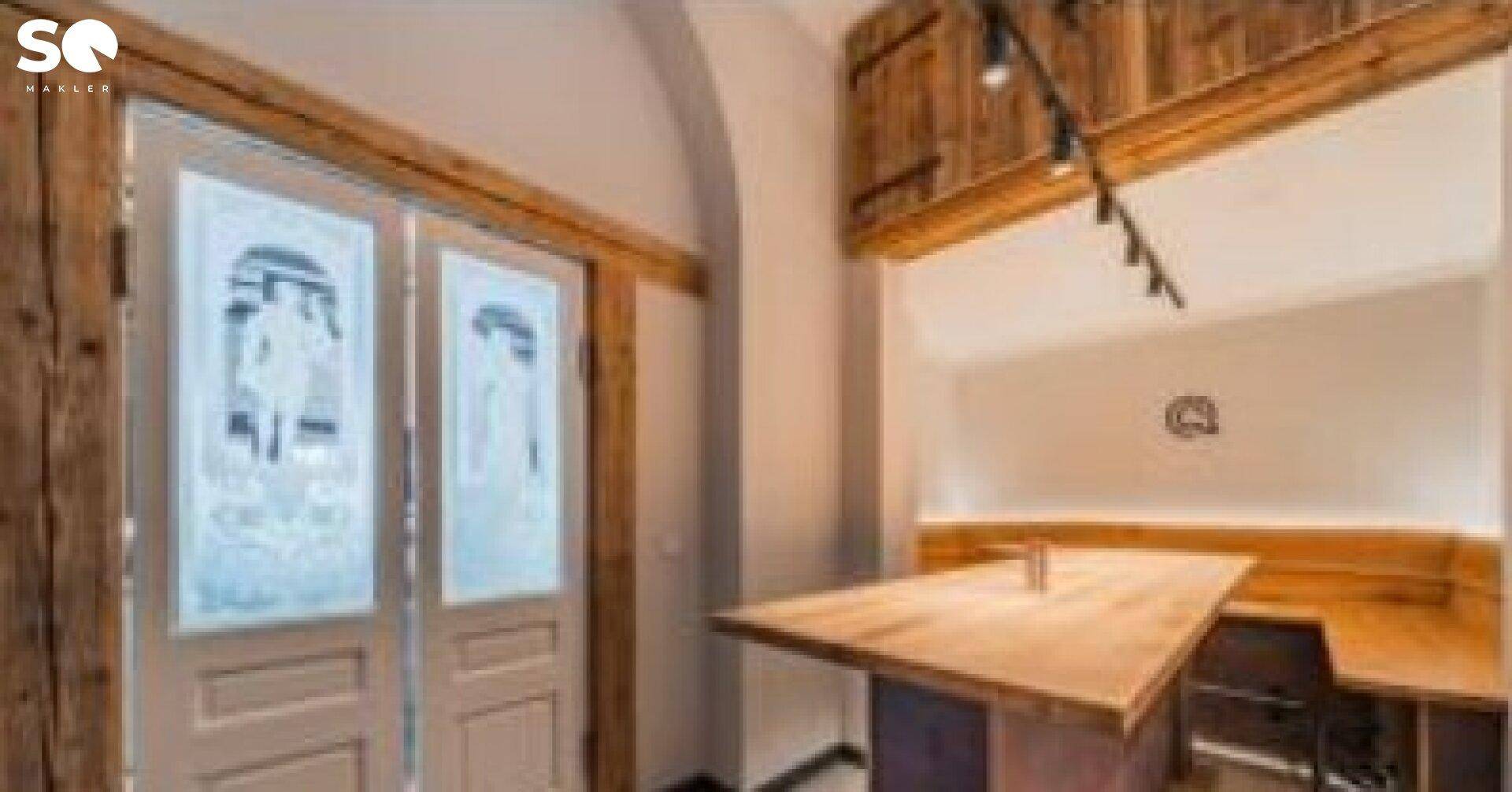 Privater Essbereich mit Holztisch und eingebauter Sitzbank, umgeben von rustikalen Holzelementen und einer verzierten Tür.